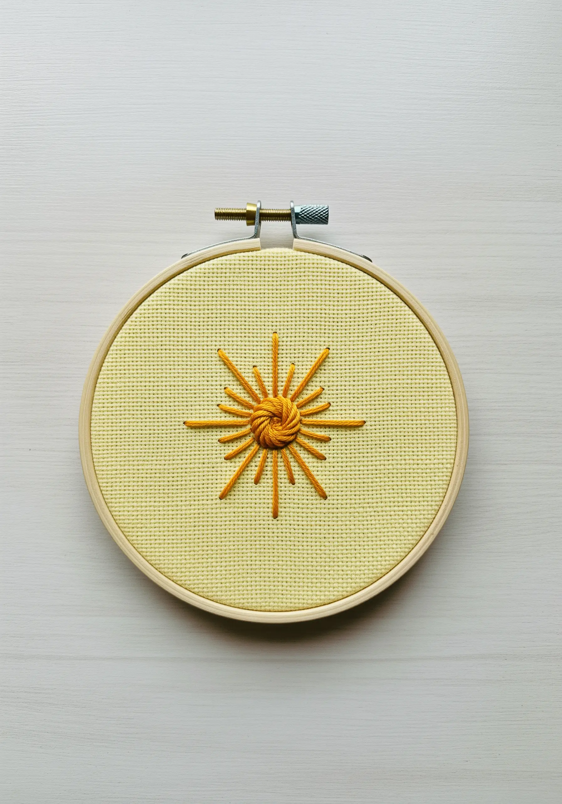 A stylized sun with a woven center and straight-stitch rays.