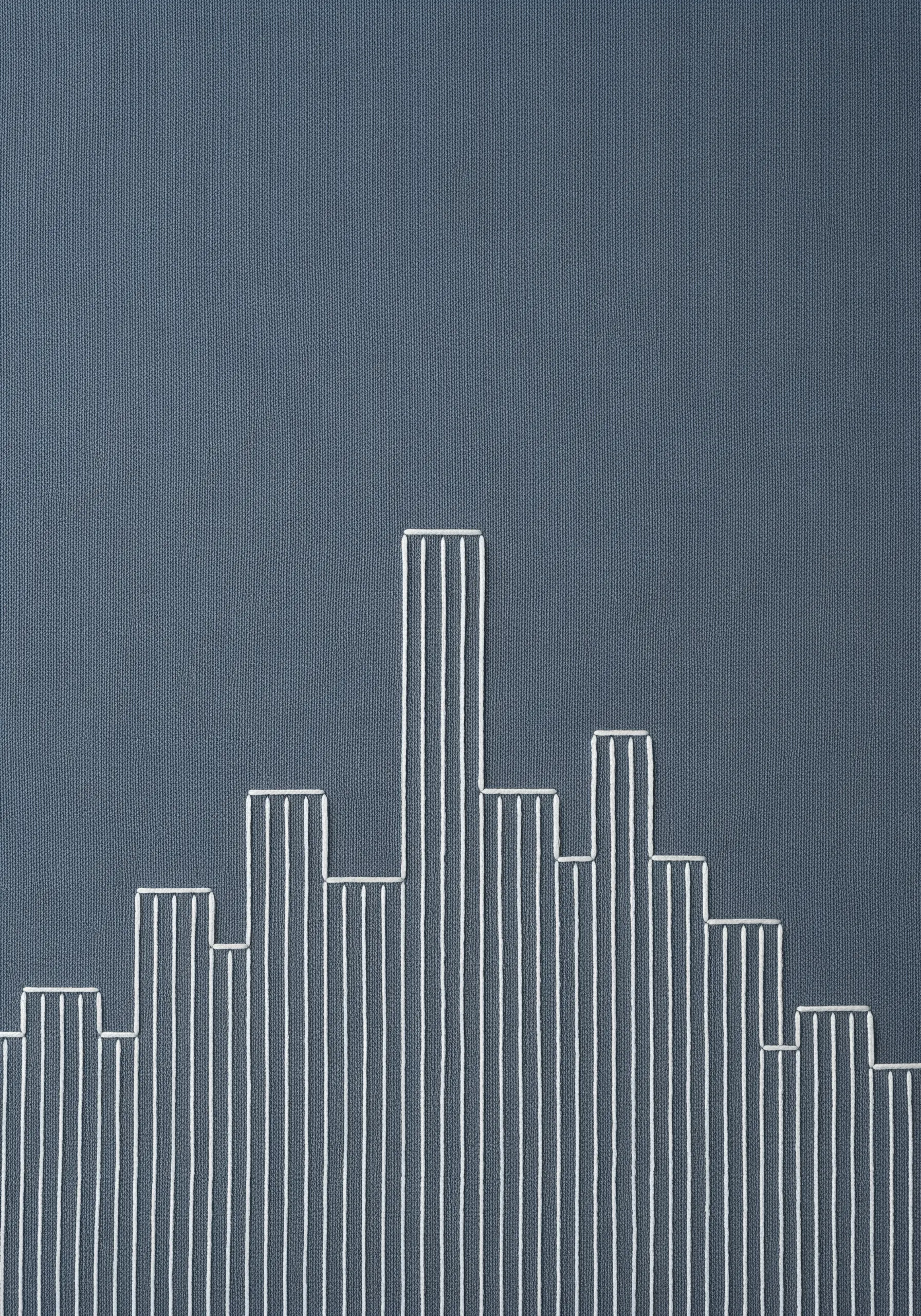 A minimalist cityscape created with vertical white straight stitches on blue-grey fabric.