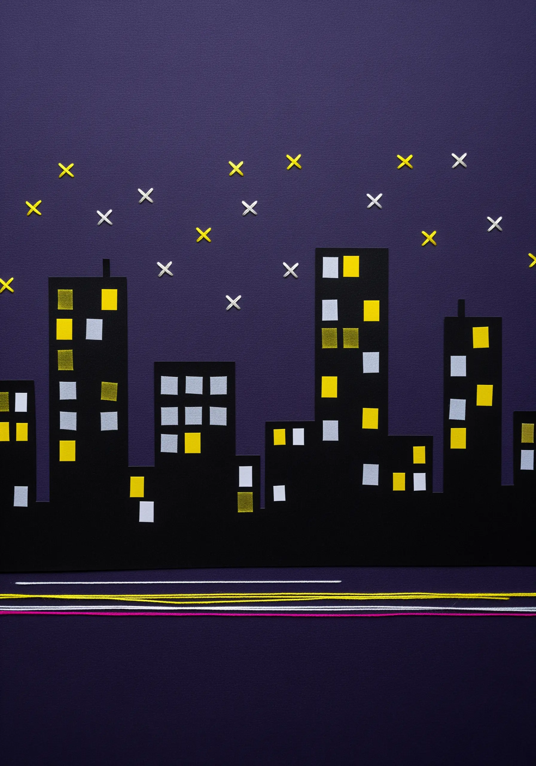 A paper collage of a city skyline at night with long, colorful threads representing light trails.