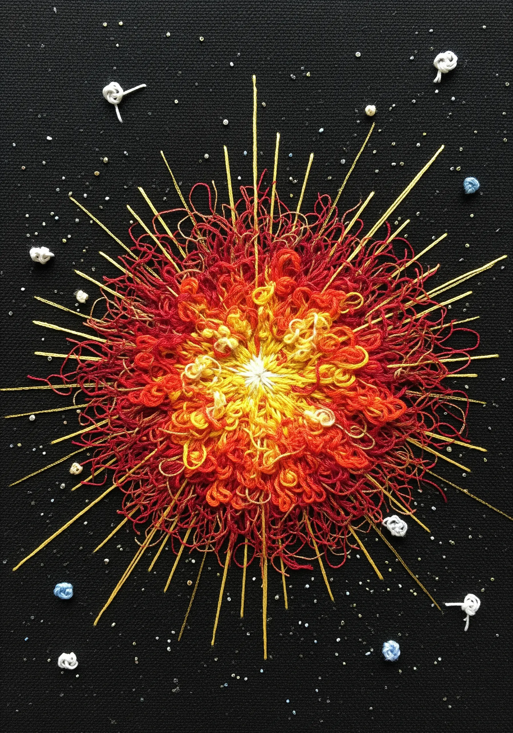 An embroidered supernova with a chaotic, looped red and orange center and radiating gold stitches.
