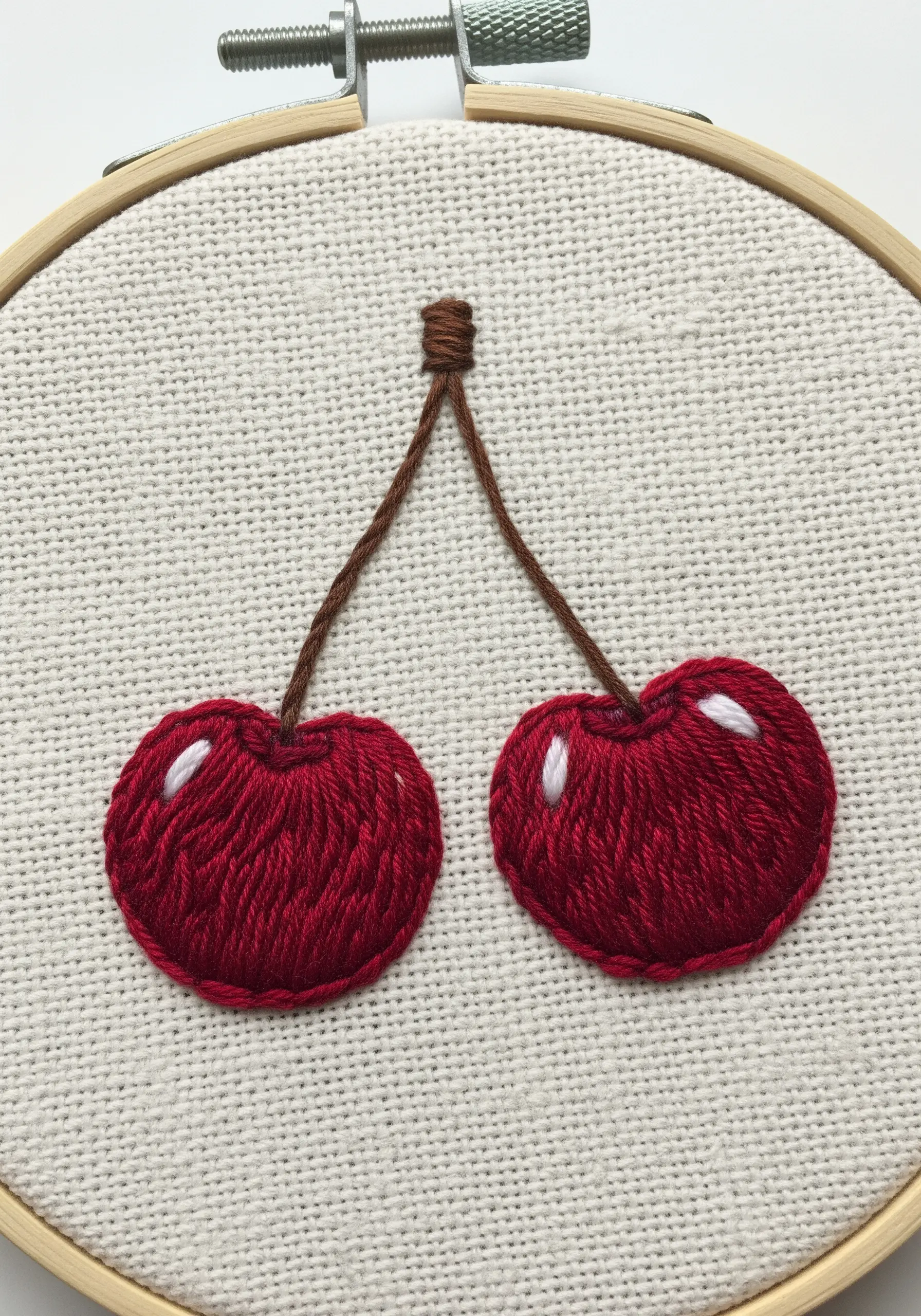 Two satin-stitched cherries with small white stitches to create a shiny highlight.