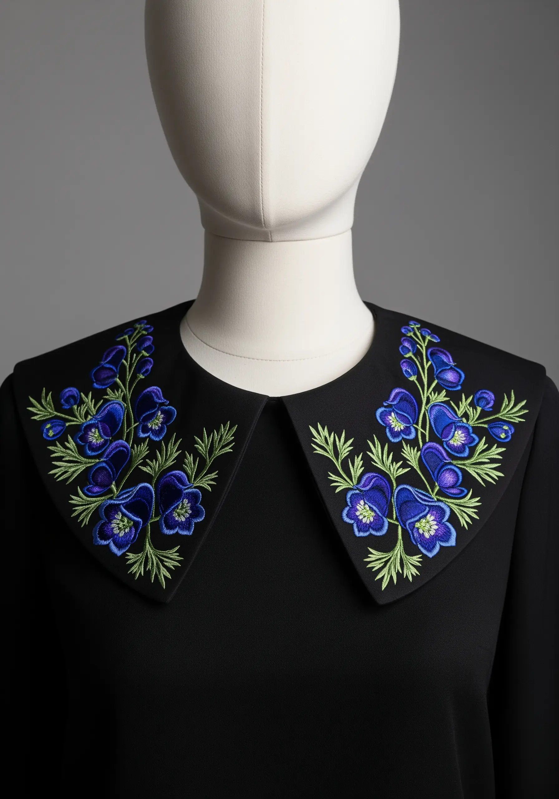 Symmetrical embroidered blue and purple flowers on the collar of a black blouse.