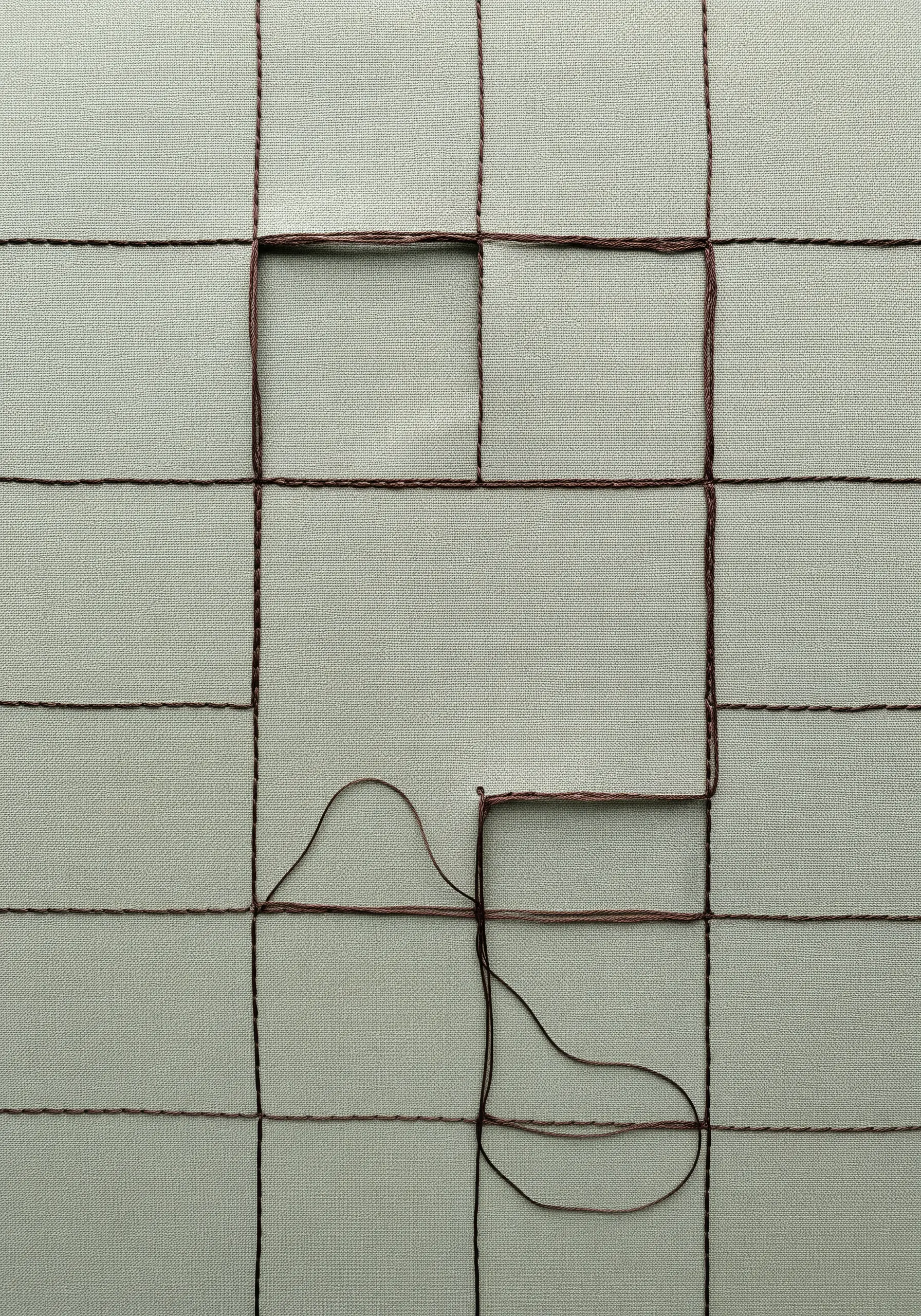 An incomplete grid stitched in brown thread, with one thread left loose.