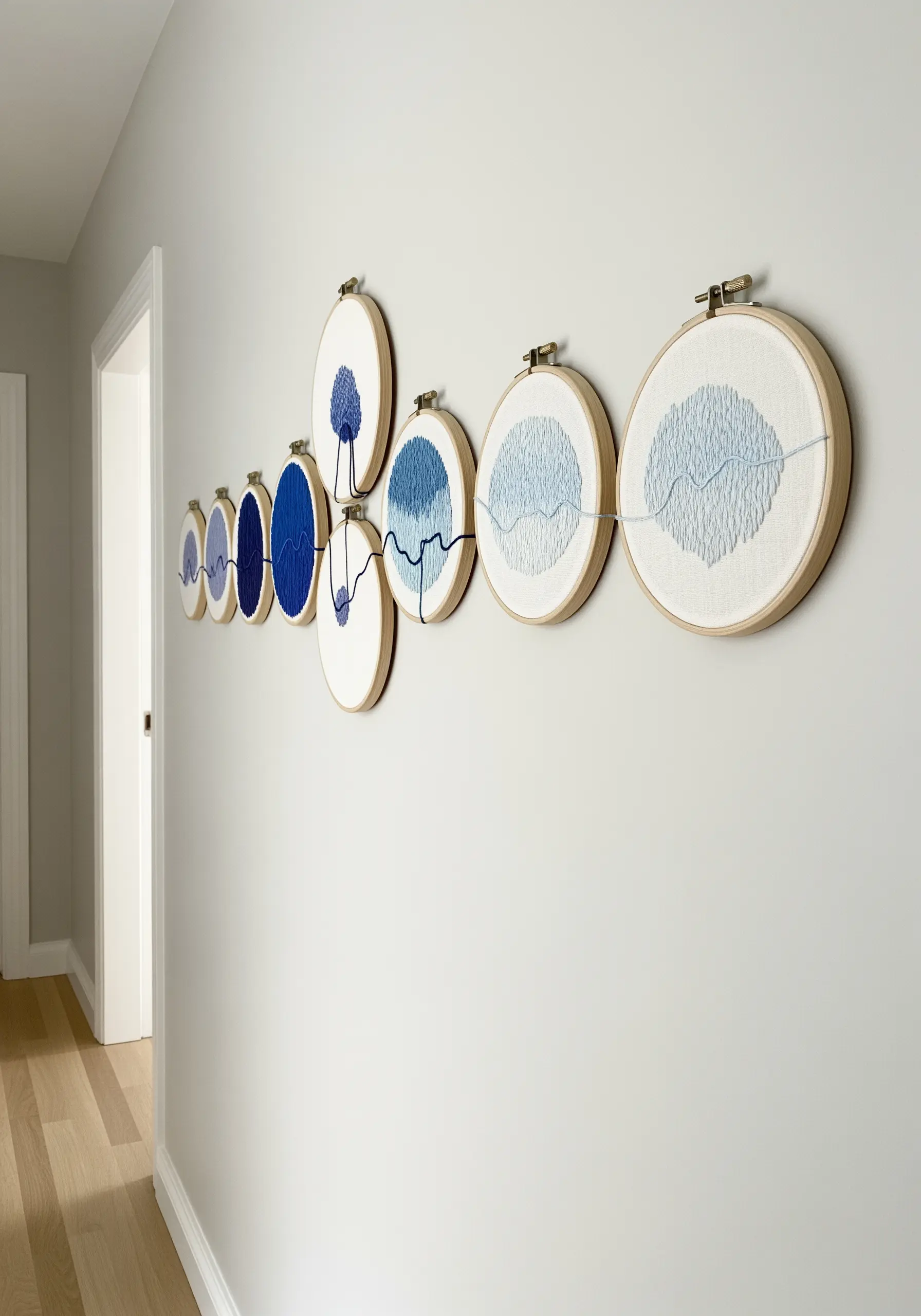 A series of embroidery hoops showing a gradient of blue with a connecting thread.
