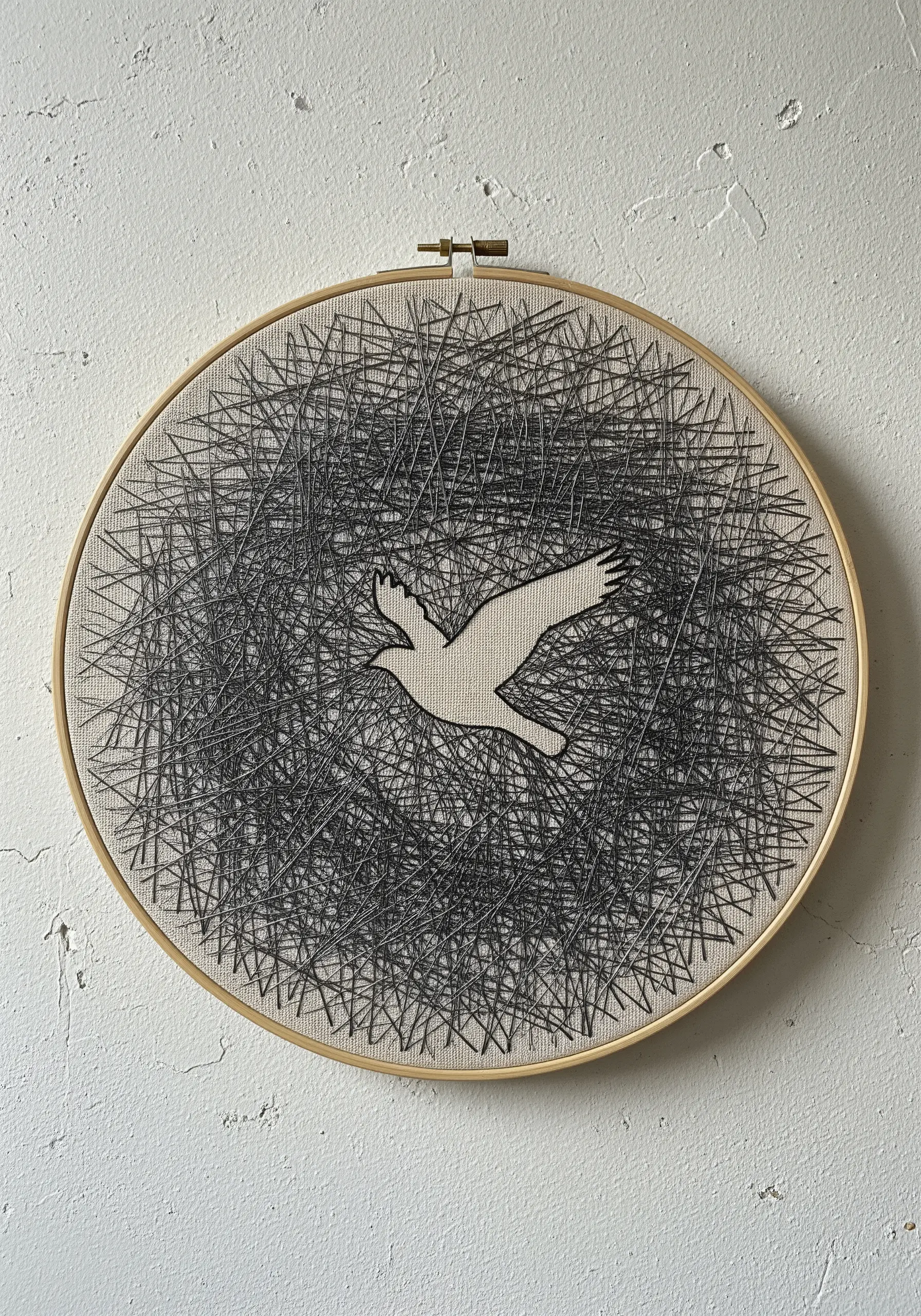 Embroidery hoop art showing a bird's silhouette in negative space, surrounded by chaotic black thread.