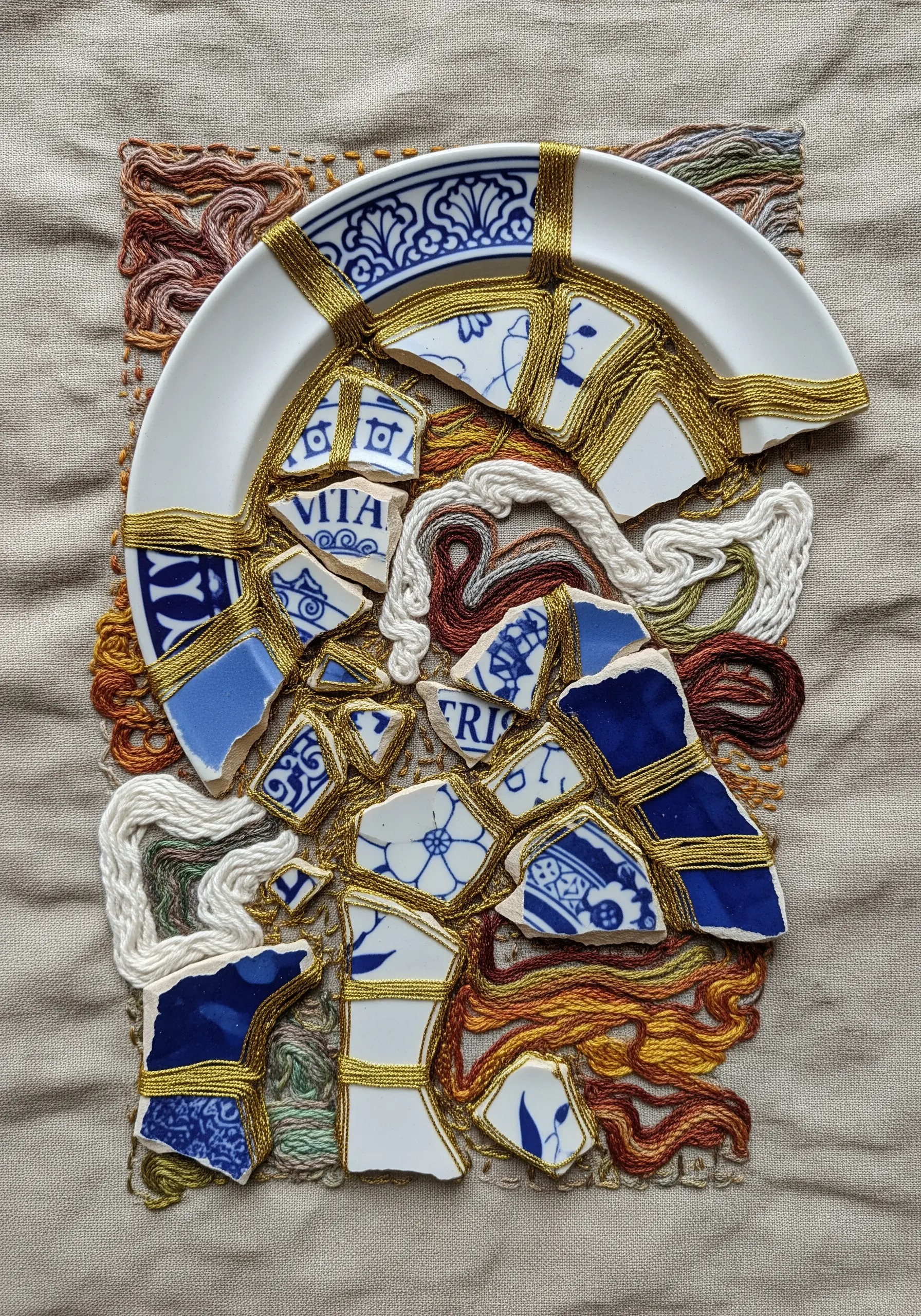 Broken ceramic plate repaired with gold thread embroidery
