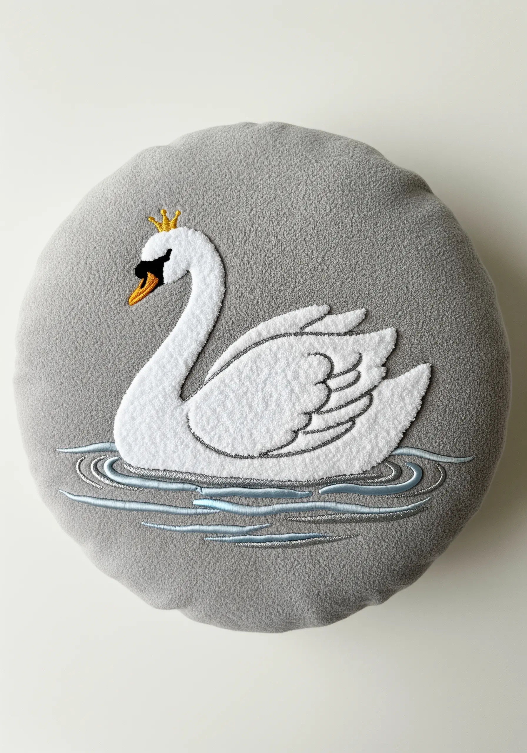 An appliquéd and embroidered crowned swan on a round grey fleece cushion.