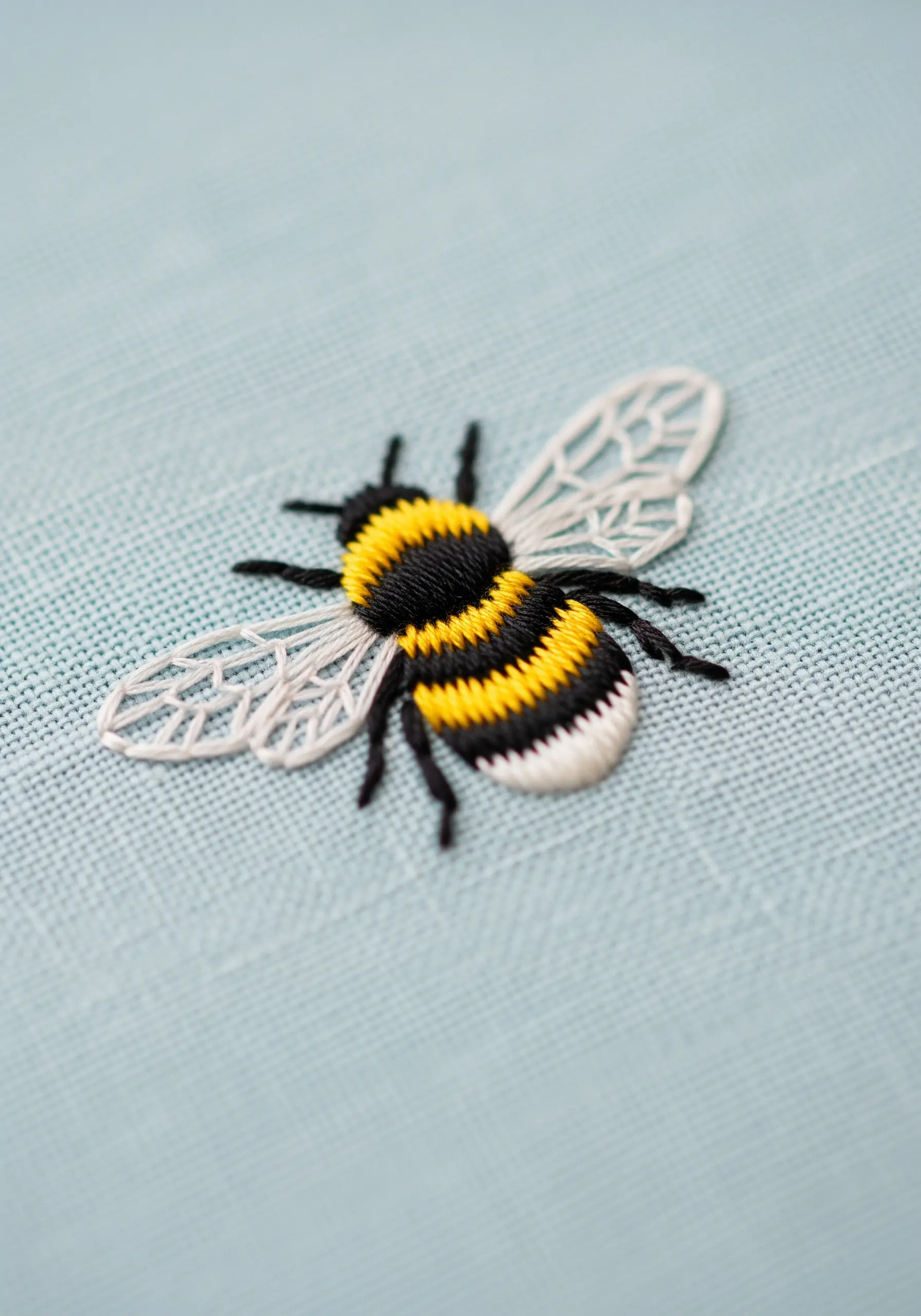 Bumblebee embroidery with dense satin stitch body and geometric wings