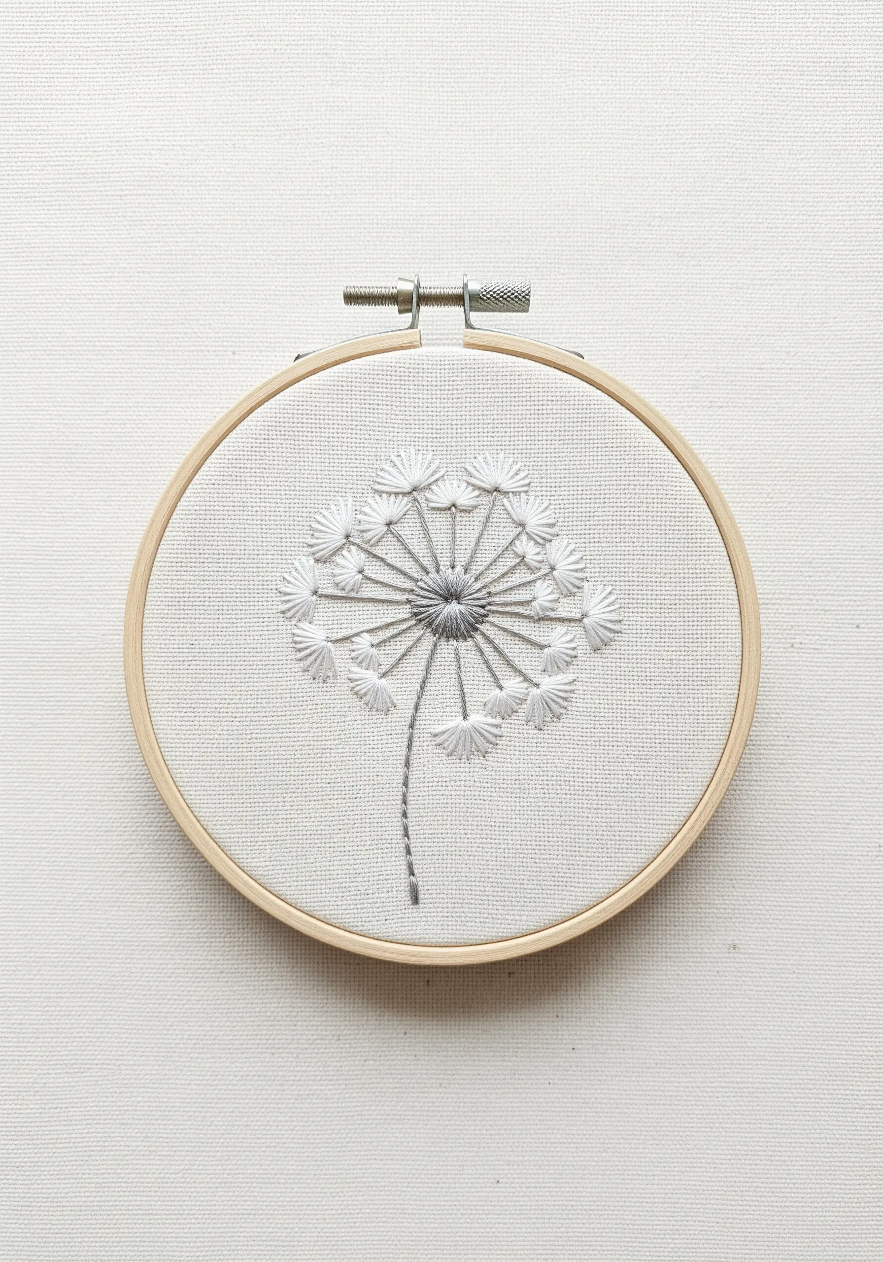 Monochrome dandelion embroidery with radiating detached chain stitches.