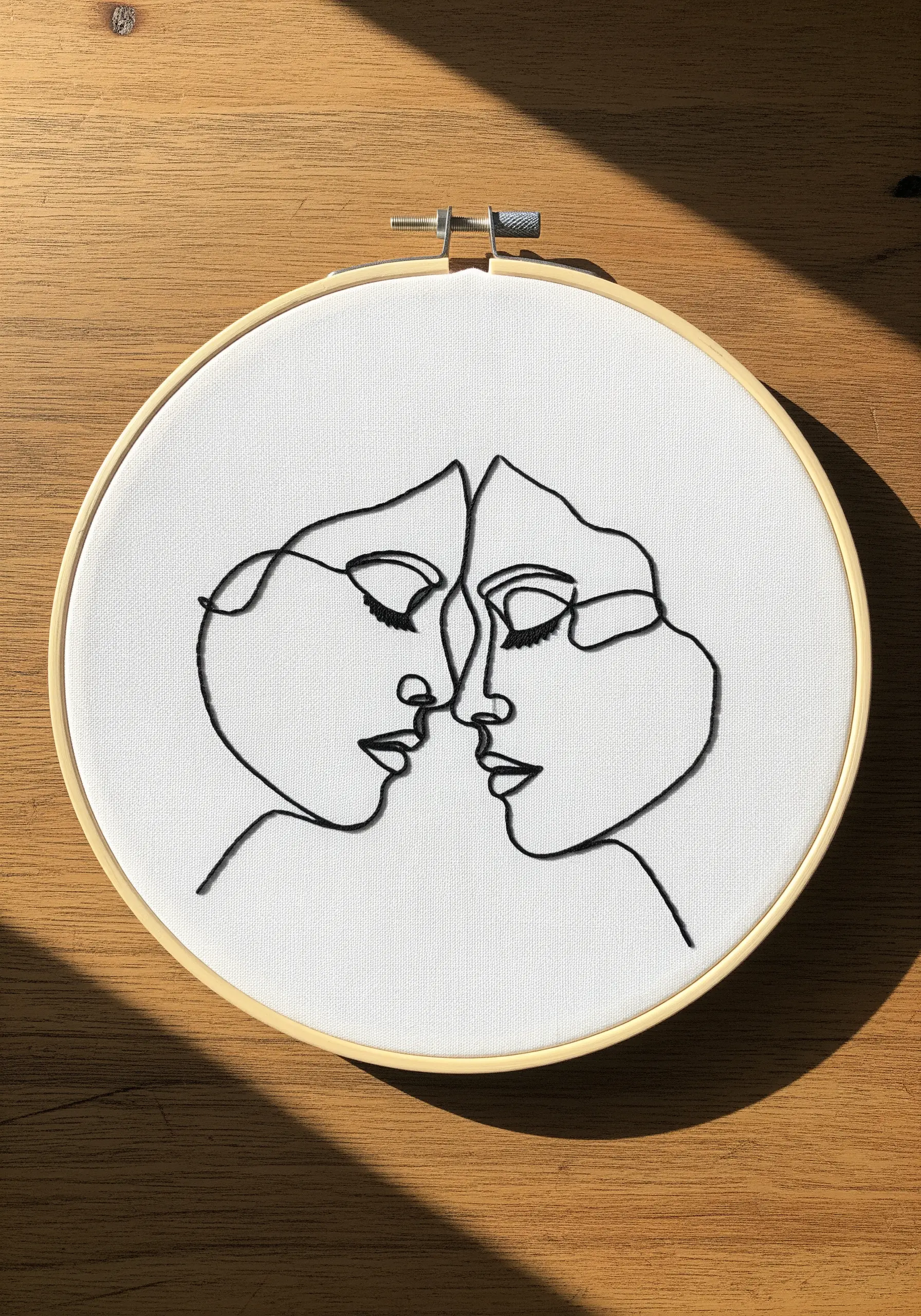 Continuous line art embroidery of two faces touching noses in black thread.