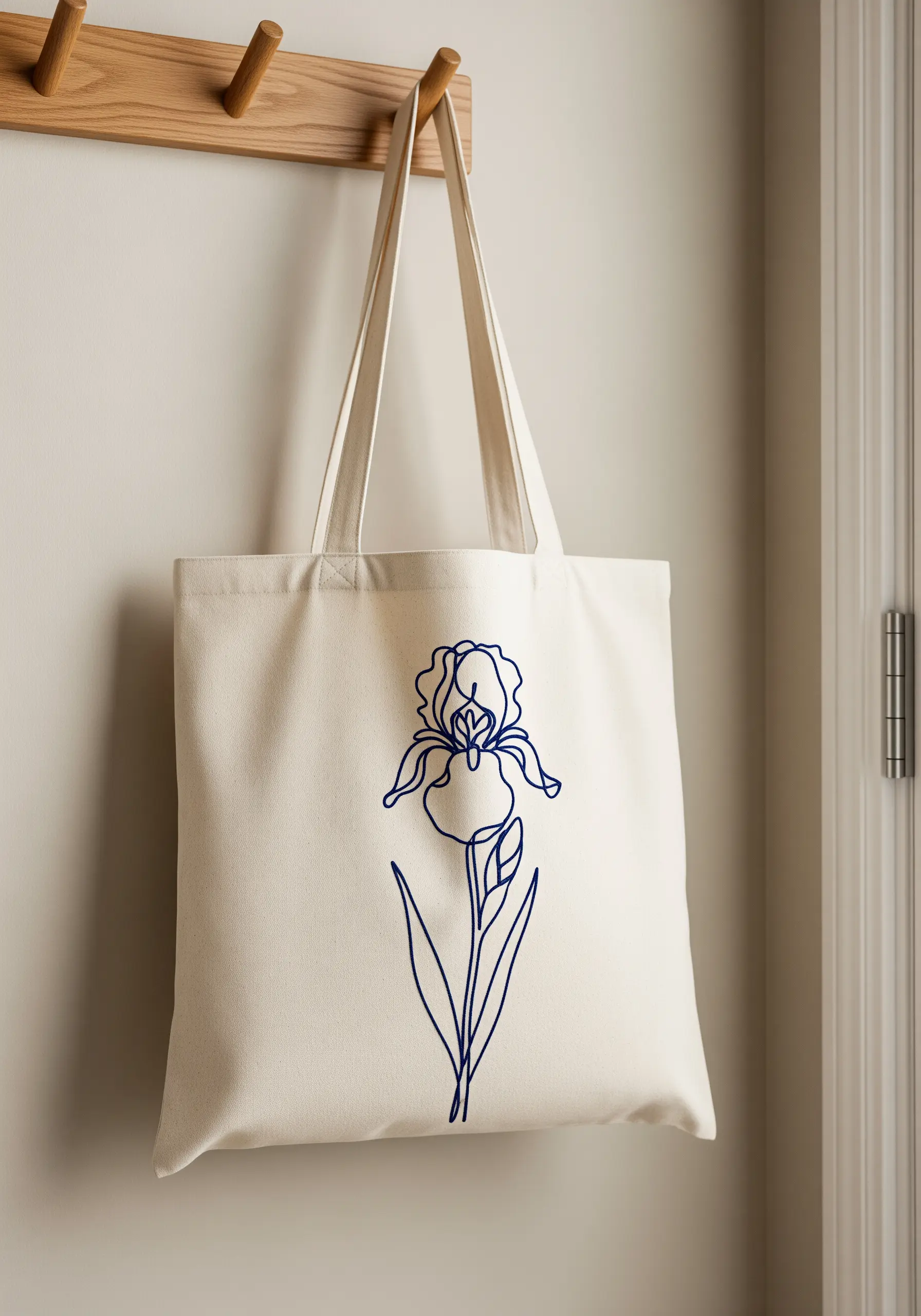 Single-line iris flower embroidered in bold blue thread on a canvas tote bag.