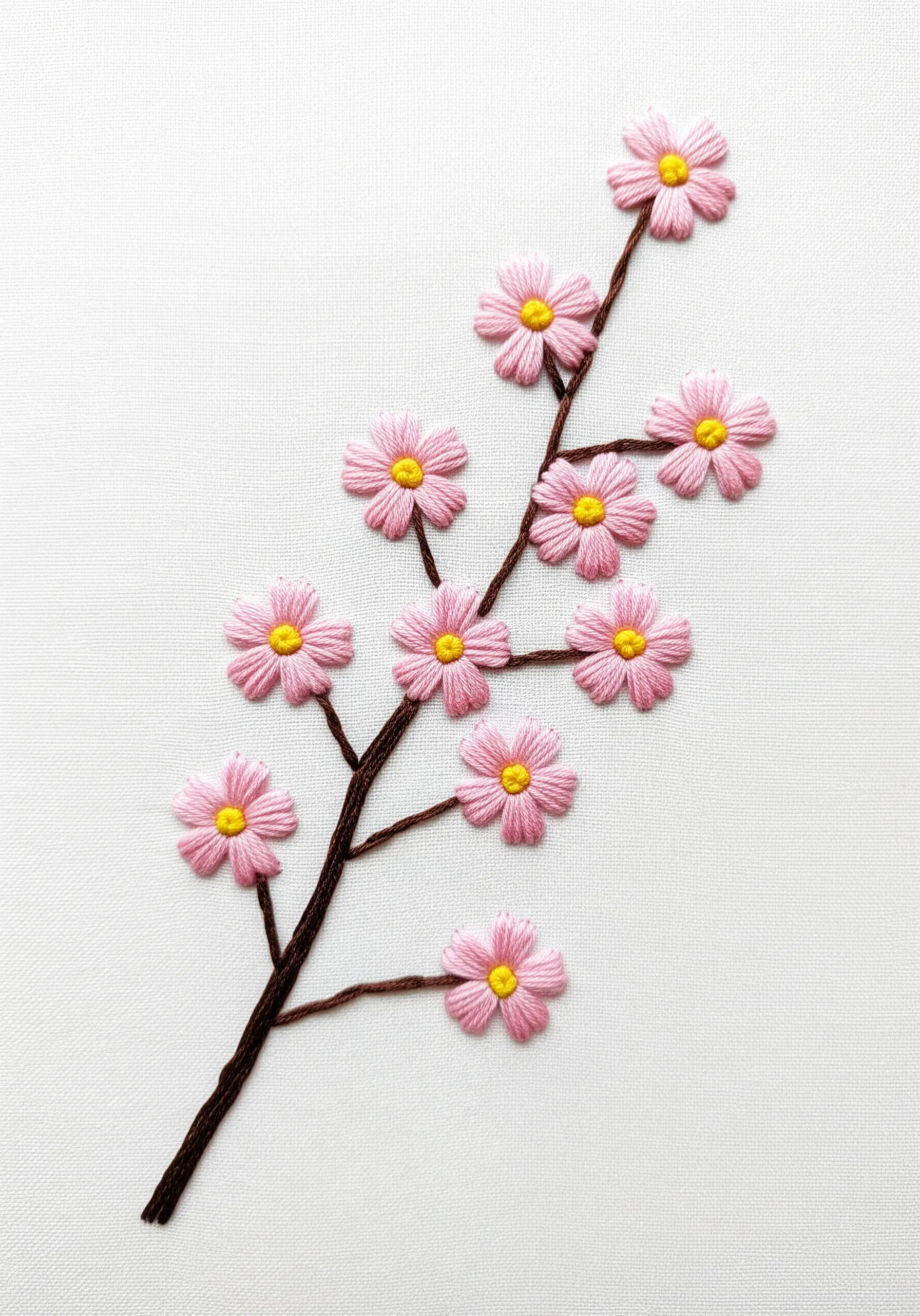 A branch of cherry blossoms made with pink lazy daisy stitches and yellow French knots.