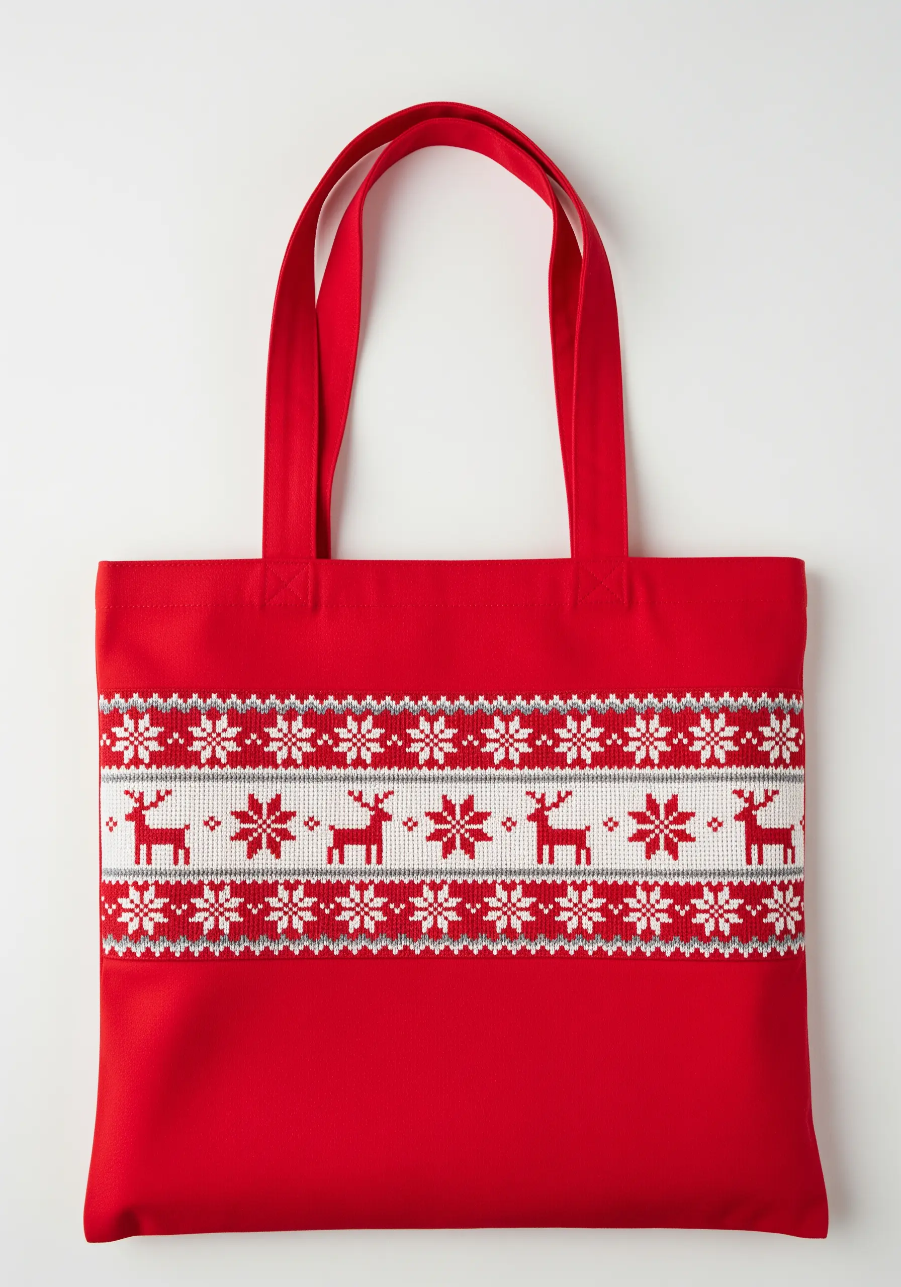 A red tote bag embroidered with a white, gray, and red Fair Isle pattern of reindeer and snowflakes.