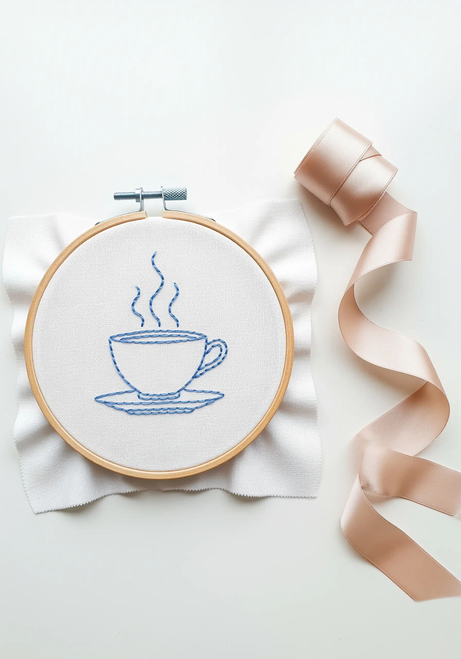 Minimalist line art of a steaming coffee cup embroidered in blue thread.