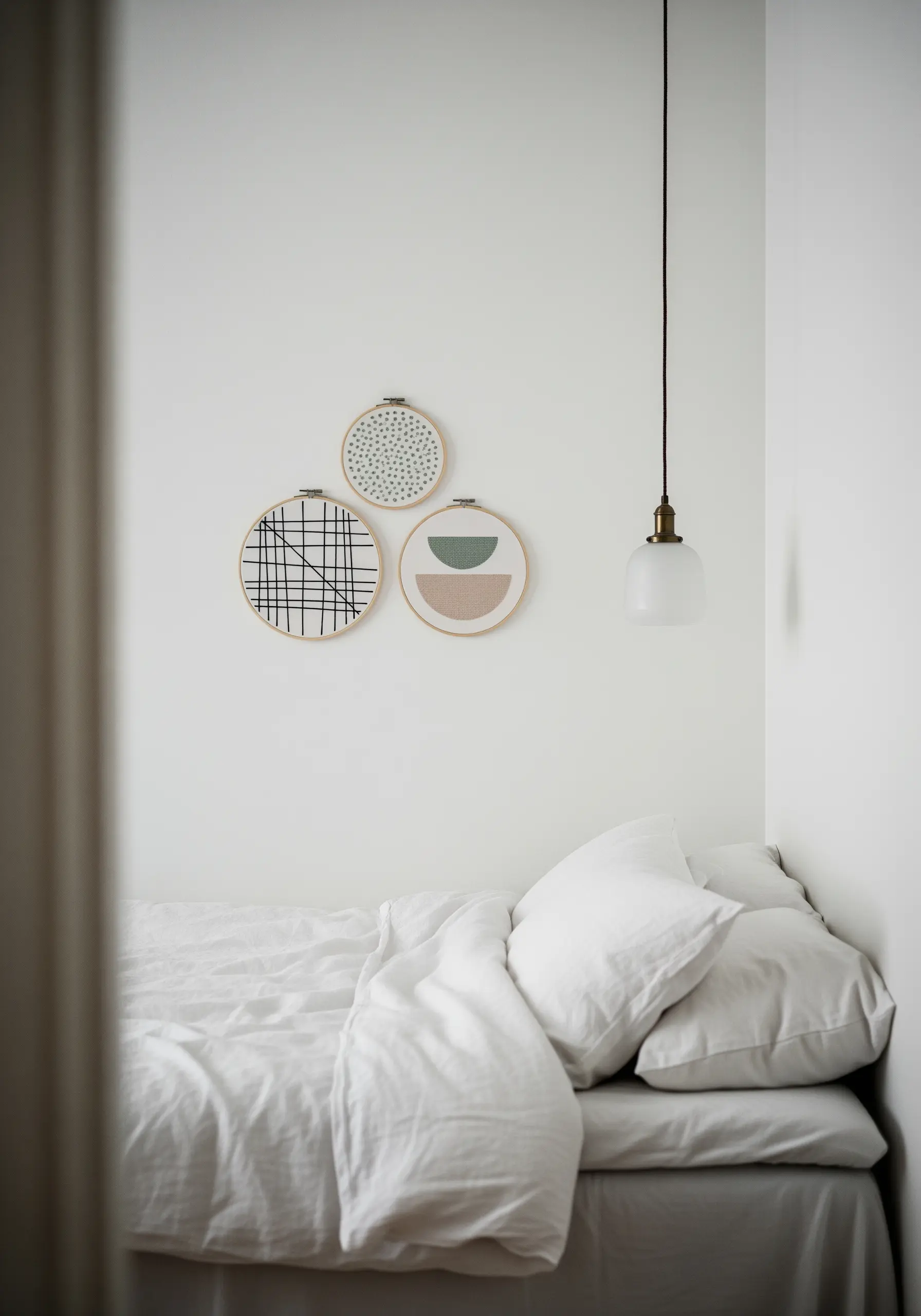 Three small embroidery hoops with minimalist geometric designs in a cohesive color palette.