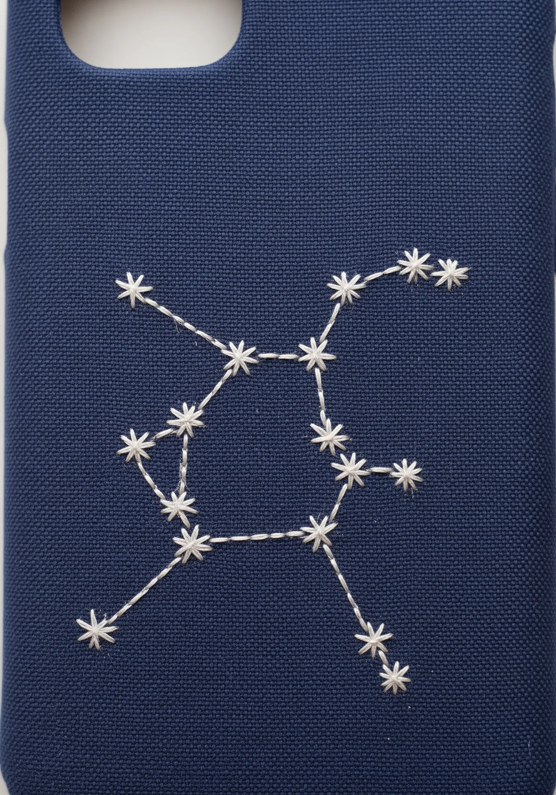 A star constellation embroidered in white thread on a dark blue phone case.