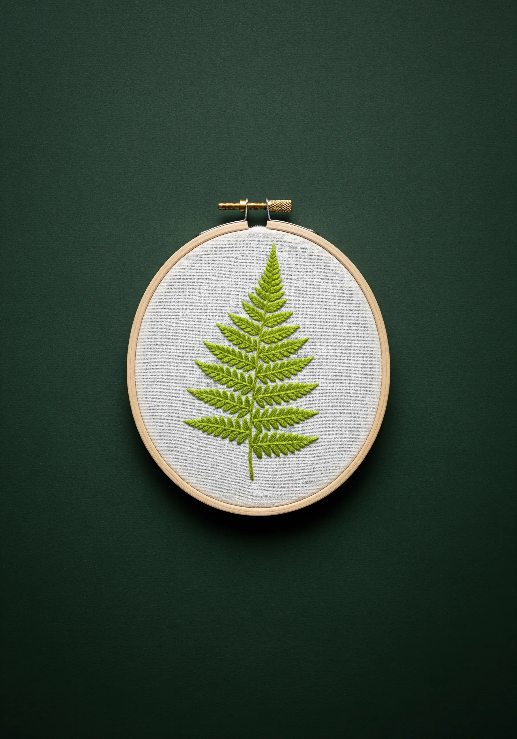 A realistic green fern leaf embroidered with precise, repetitive stitches on white fabric.