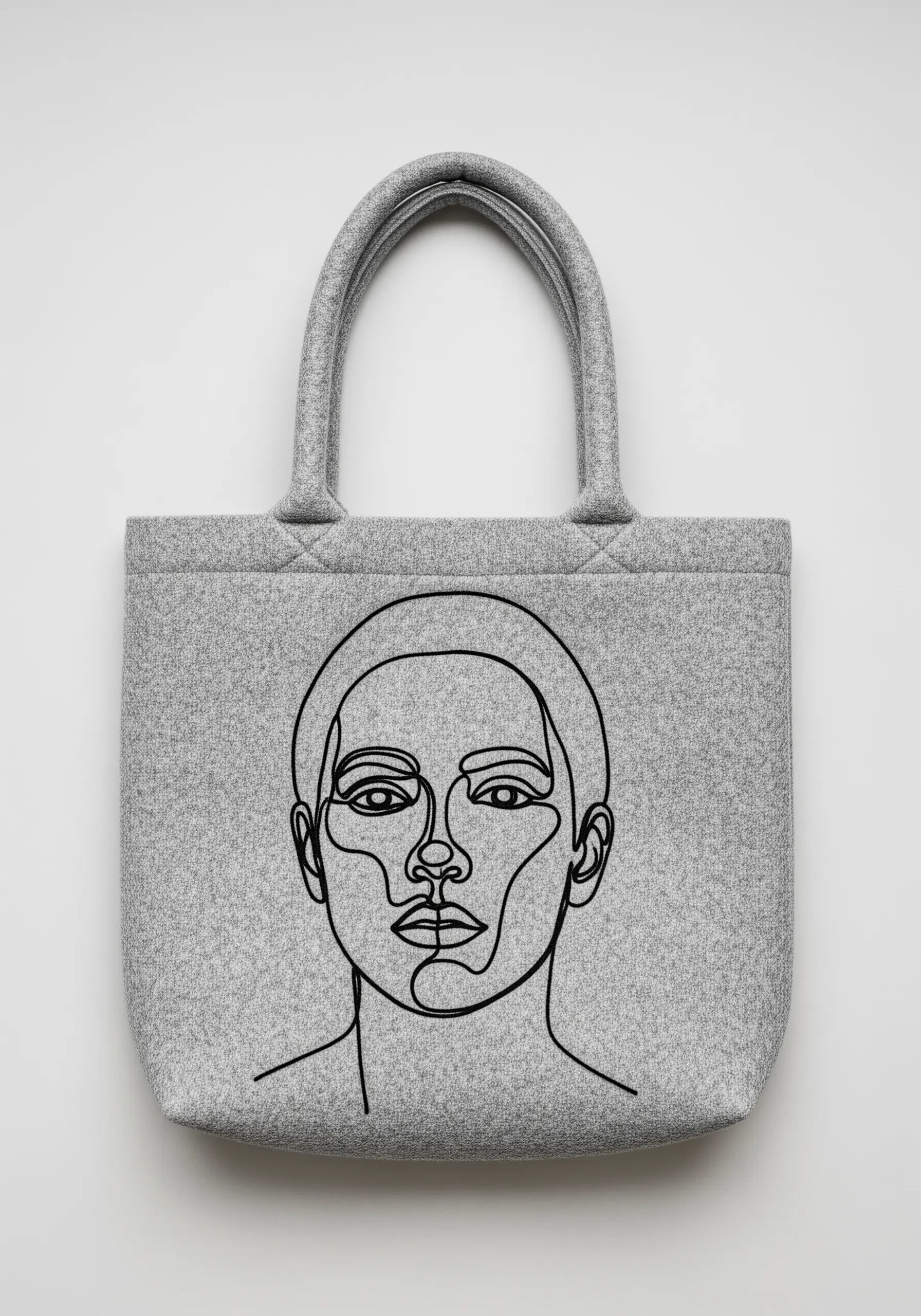 A close-up of a modern single-line portrait embroidered in black thread on a grey felt tote bag.