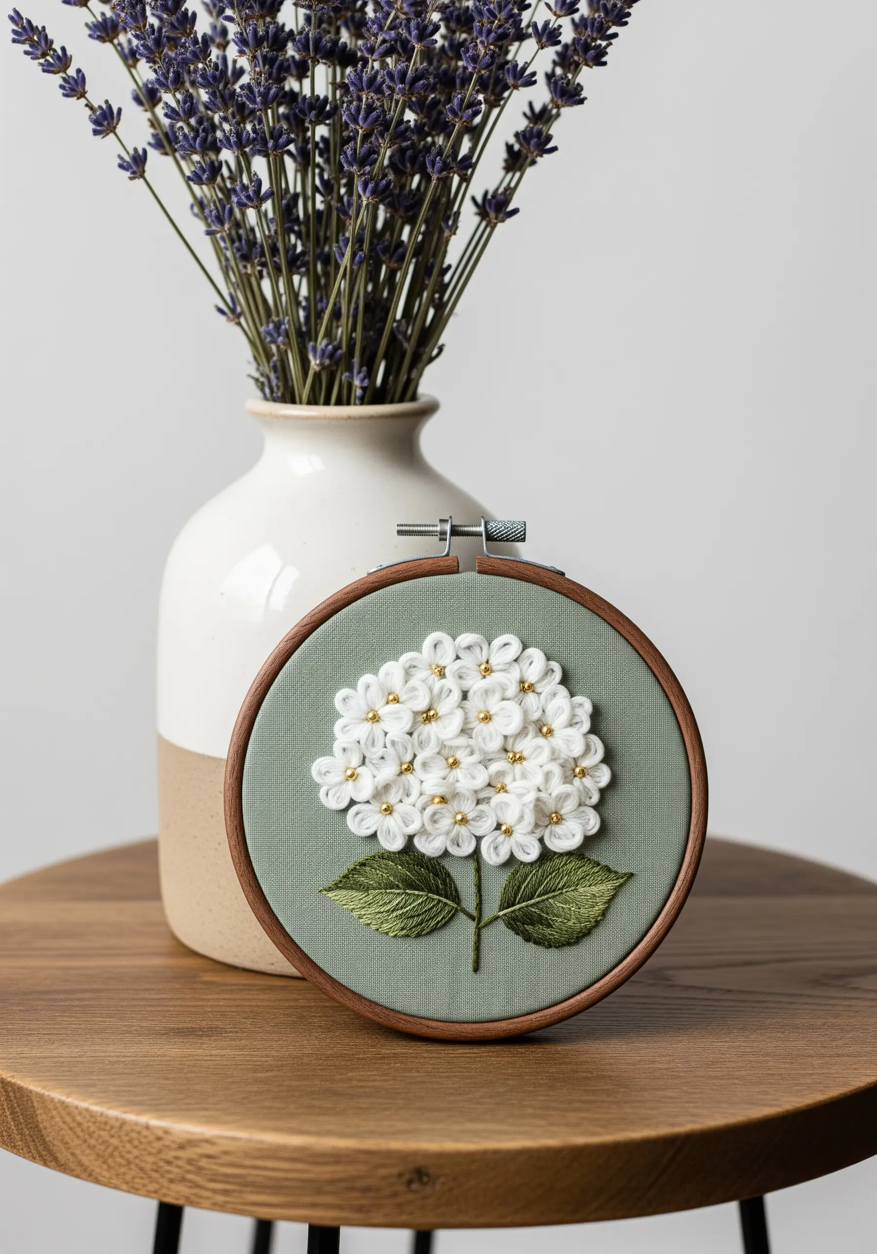 White hydrangea with bullion knot petals and gold bead centers on sage green linen.