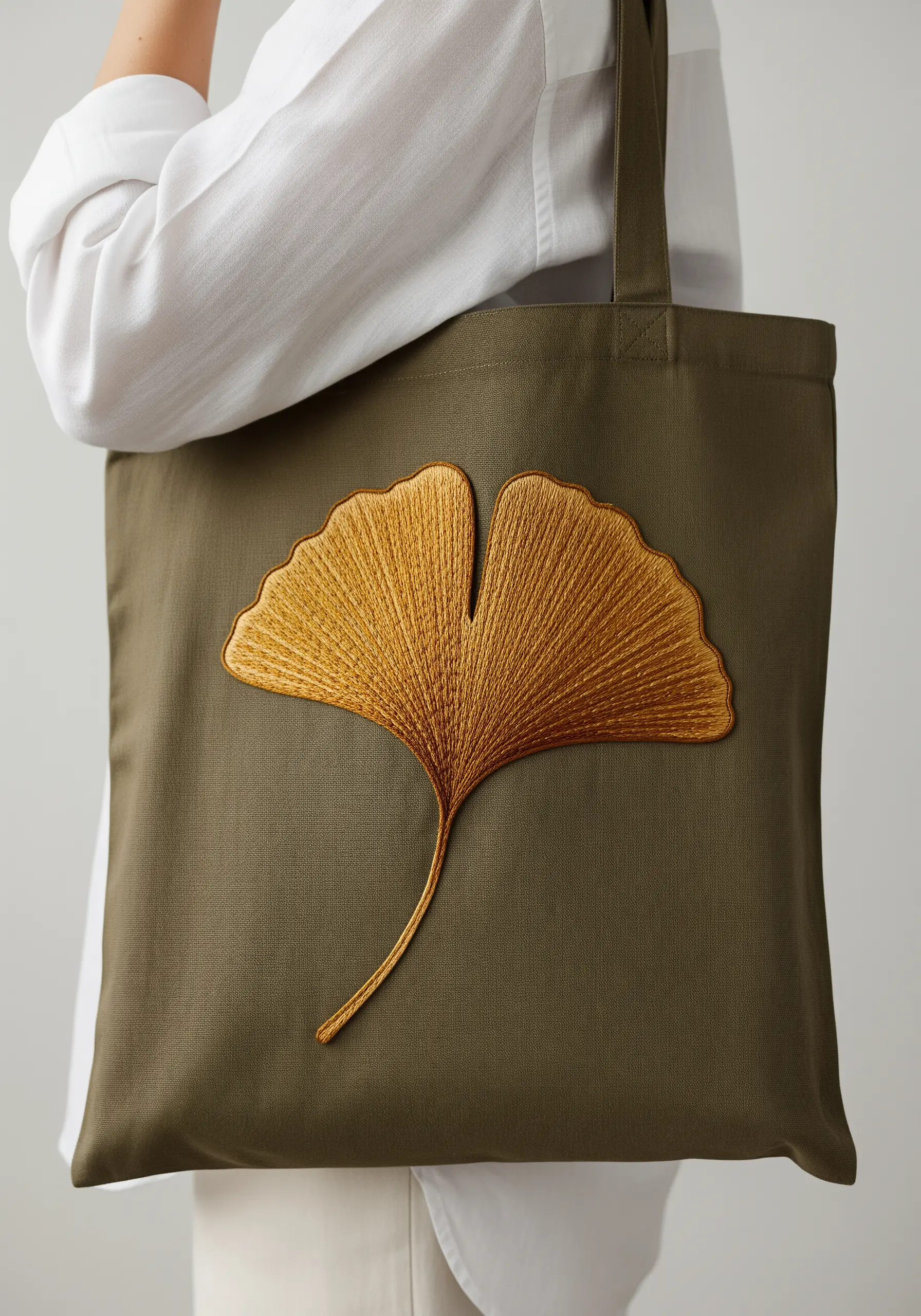 A single, large ginkgo leaf embroidered with realistic thread painting in gold tones.