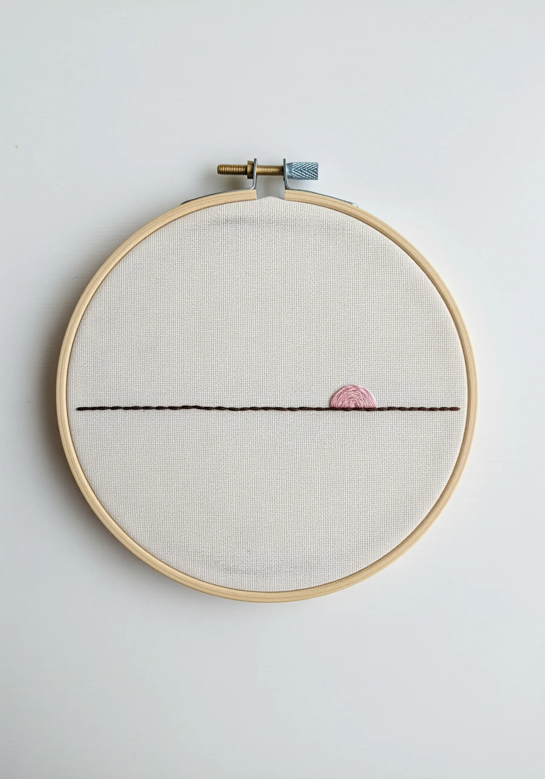 A minimalist embroidered sunset with a straight horizon line and a small satin-stitched sun.