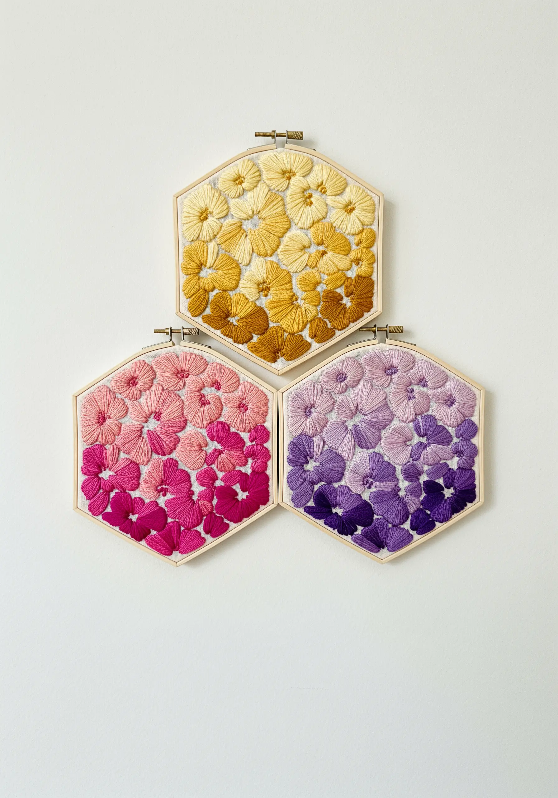 Three hexagonal hoops, each filled with gradient flowers in yellow, pink, and purple tones.