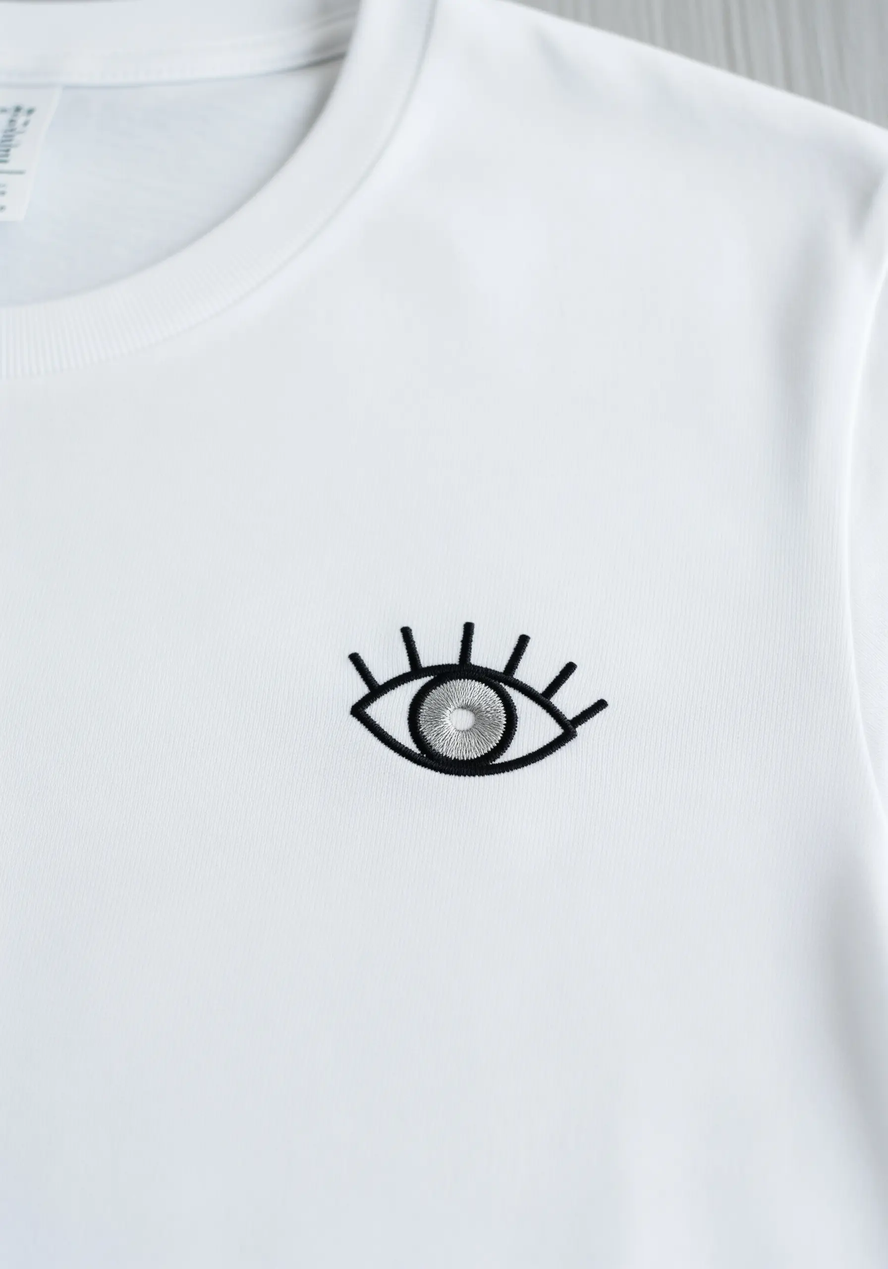 A stylized eye with a detailed iris and bold lashes near the collar.