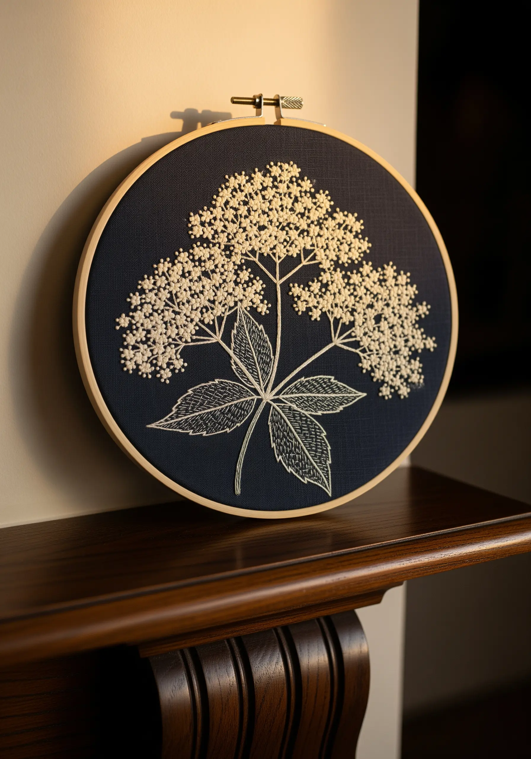 Monochrome embroidery of elderflower using white French knots on dark navy fabric.