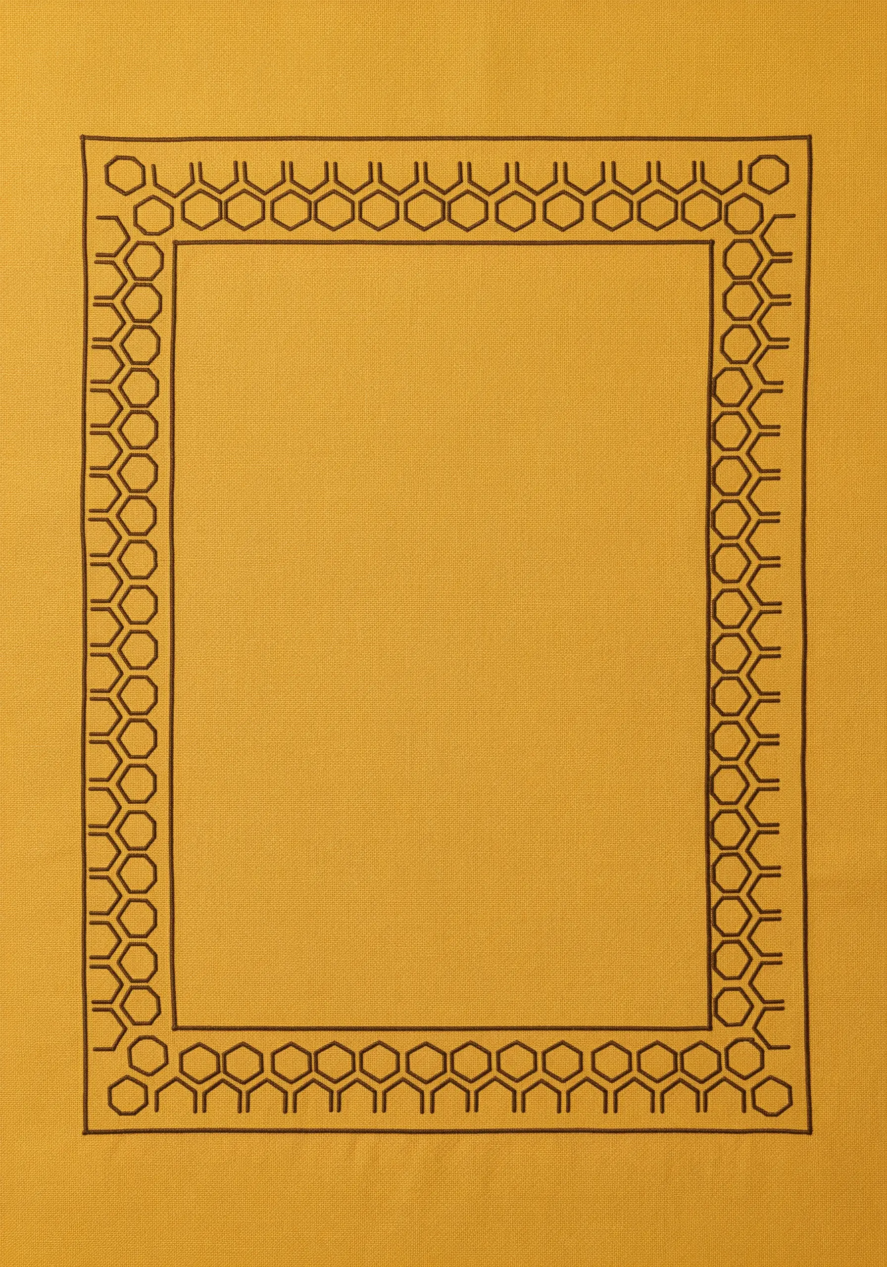 A placemat with a geometric border made of a repeating honeycomb pattern in dark thread.