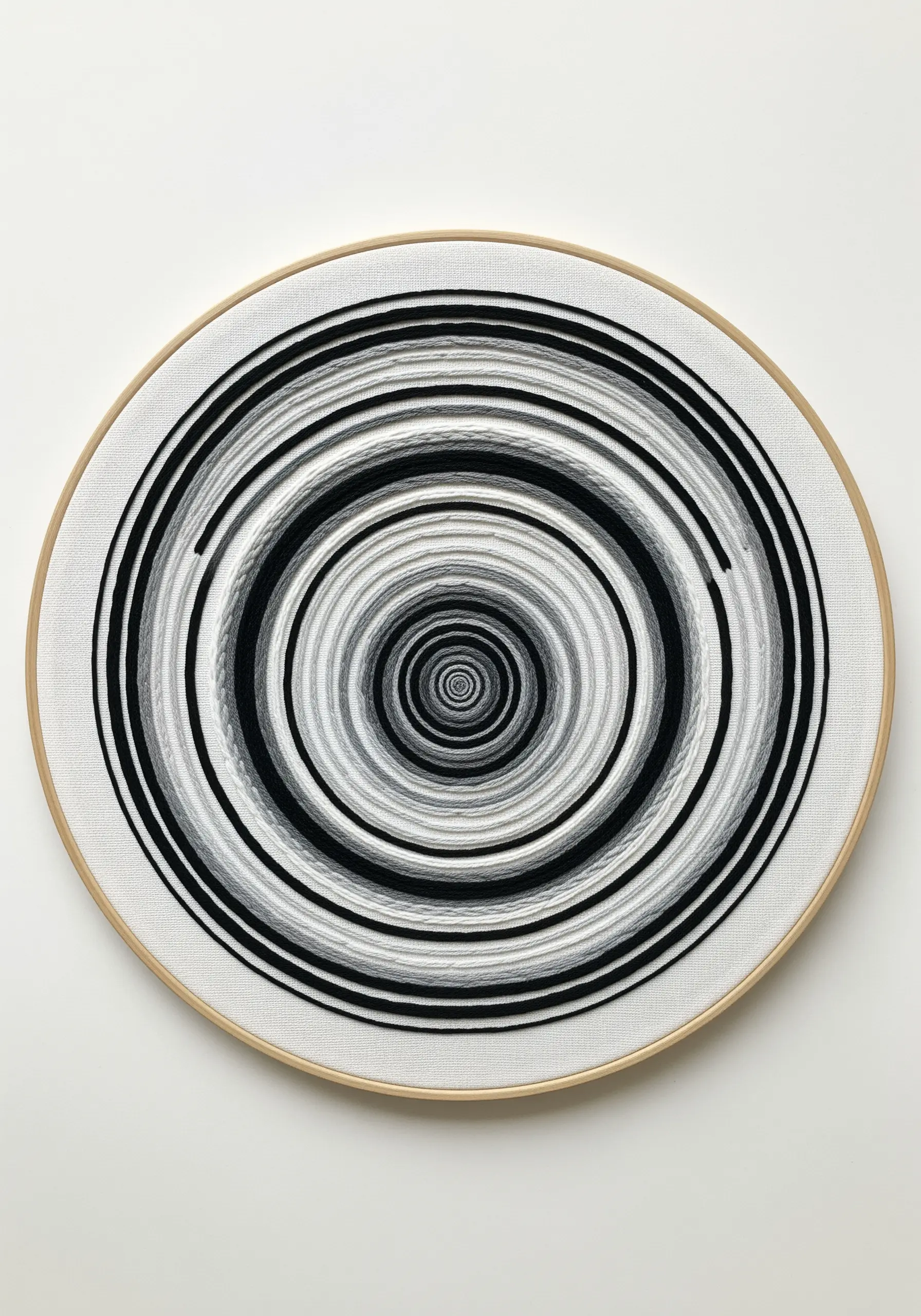 Black, white, and grey concentric satin stitch circles creating an optical illusion.