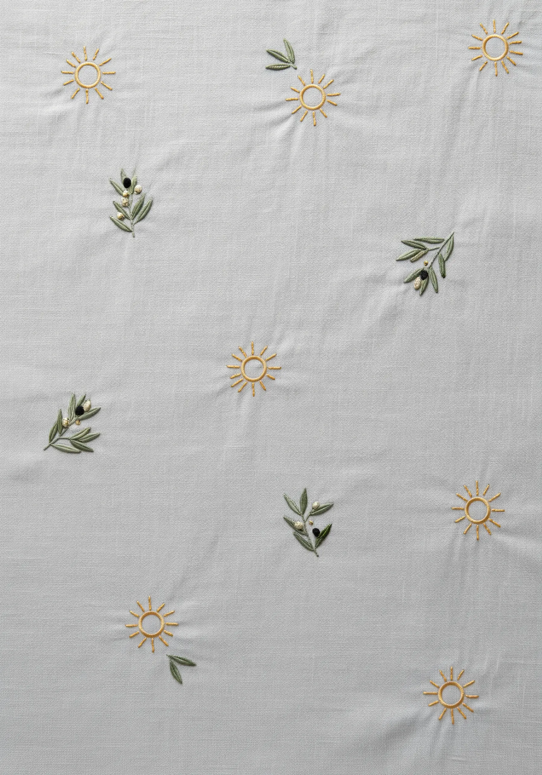 Light grey linen with small, delicately embroidered suns and olive sprigs scattered widely.