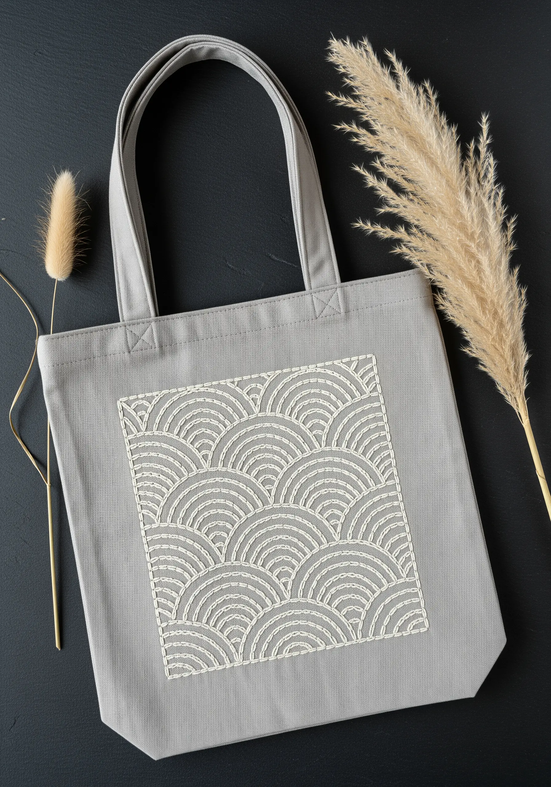 Repetitive Seigaiha wave pattern embroidered in off-white on a gray tote bag.