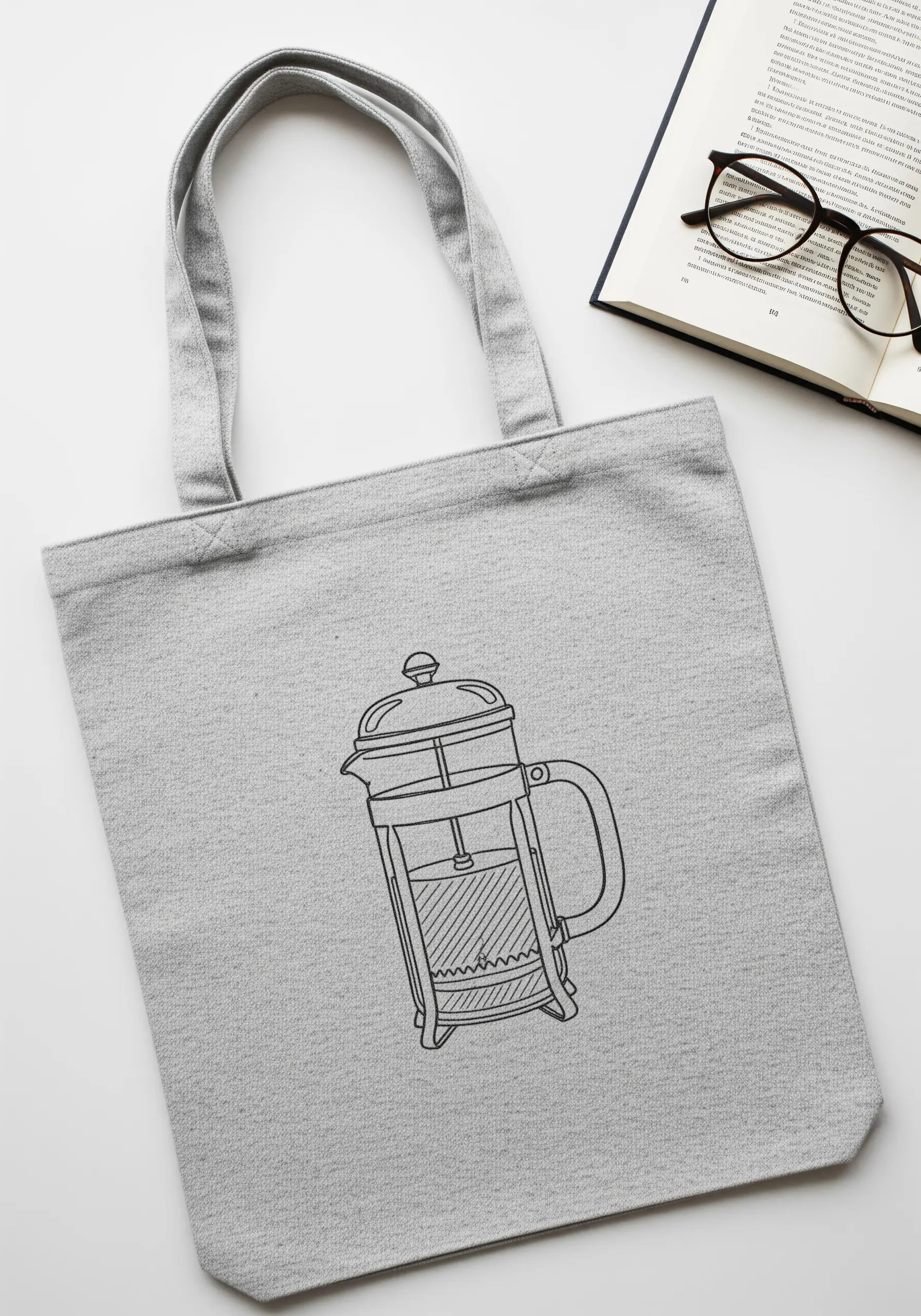 Minimalist black outline embroidery of a French press coffee maker on a gray tote bag.