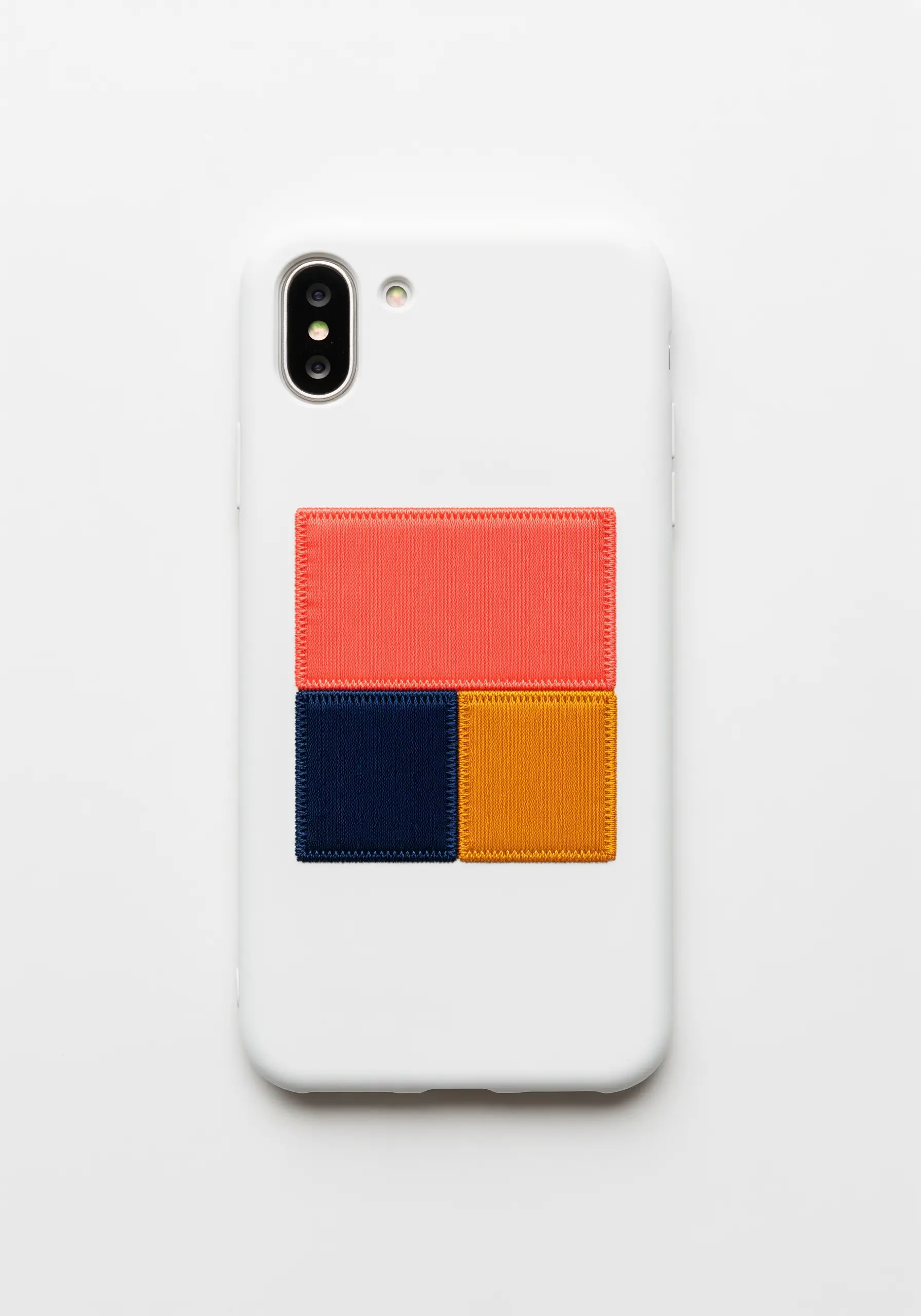 A modern geometric design with three embroidered color blocks in coral, navy, and yellow.
