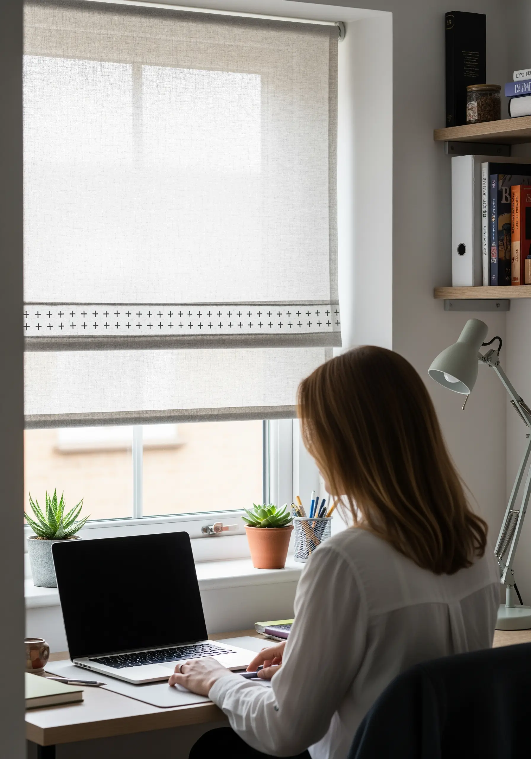 A simple cross-stitch border in black thread on a neutral window blind.