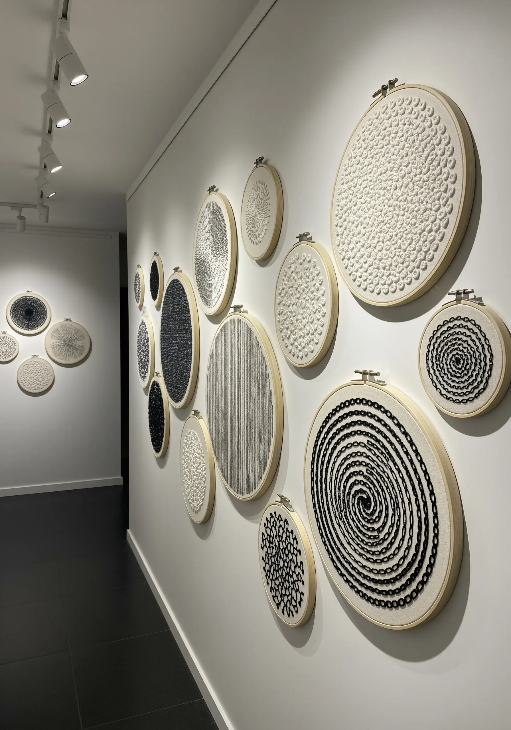 A gallery wall of embroidery hoops featuring abstract textural designs in black and white.