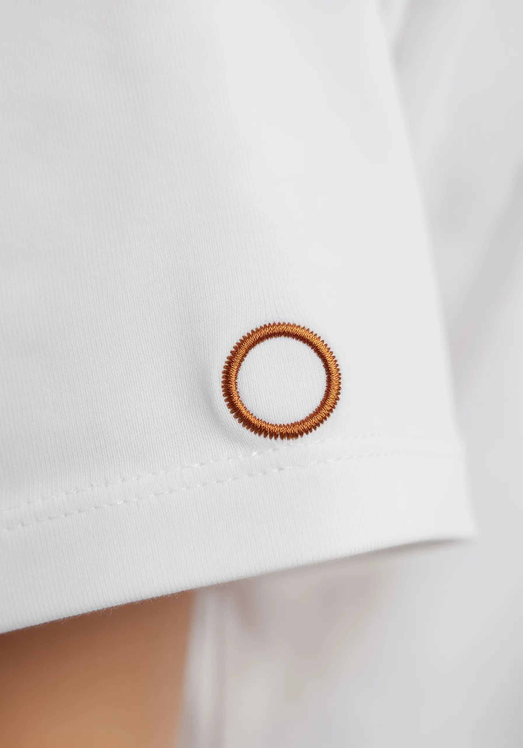 A perfectly round, raised circle in bronze satin stitch on a sleeve.
