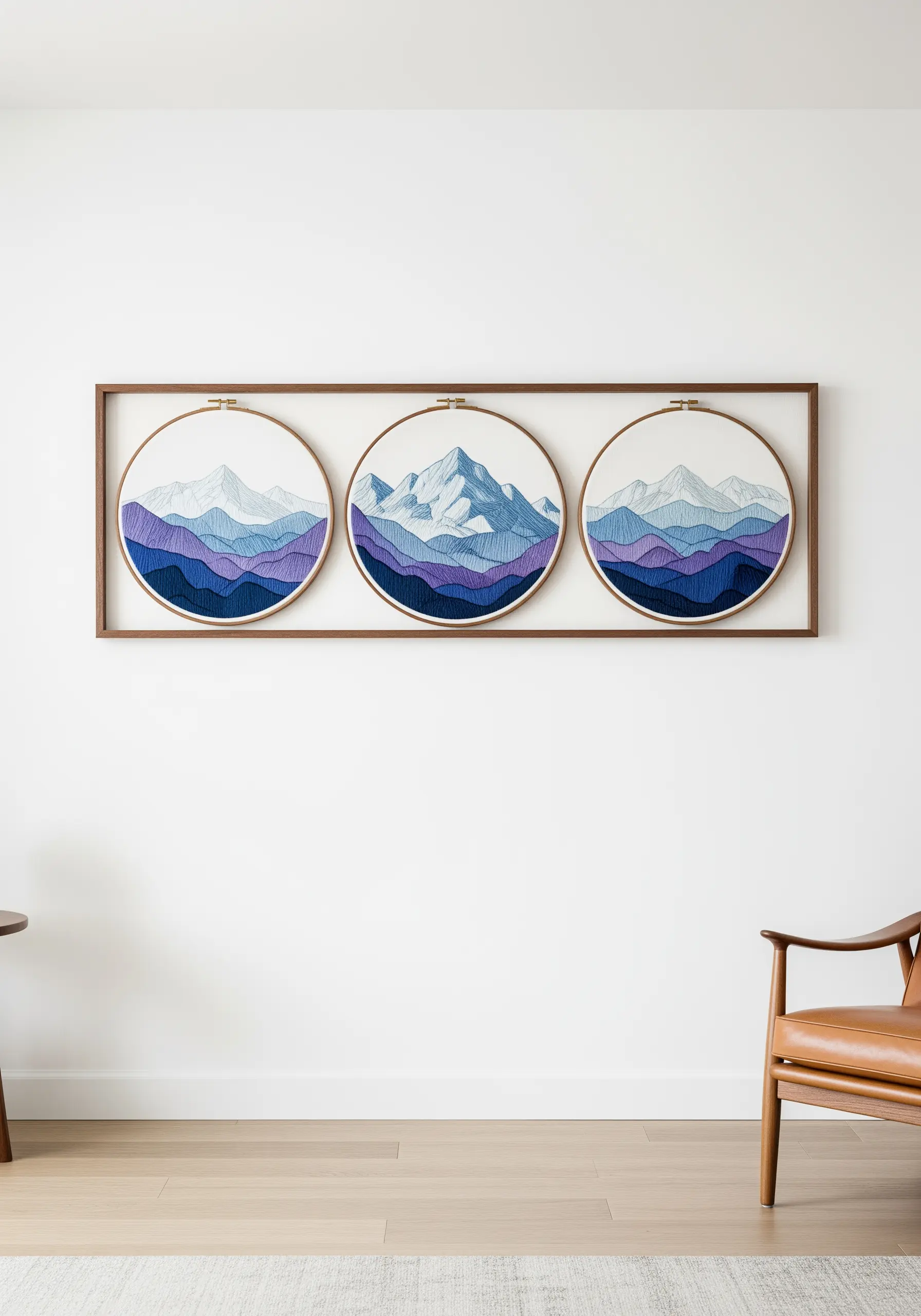 Three embroidery hoops displaying a continuous blue mountain range