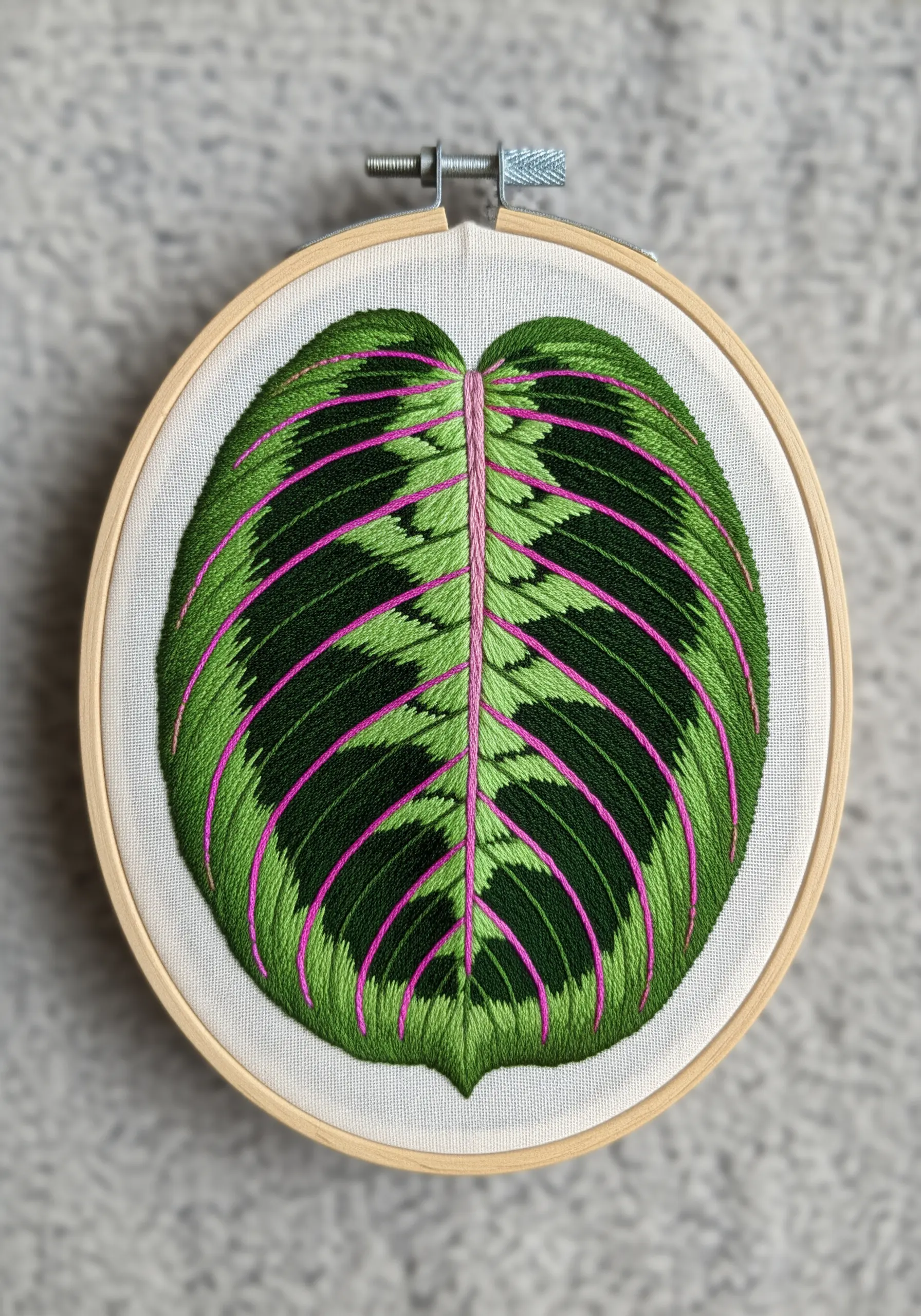 Embroidered Prayer Plant leaf with bright green patterns and vibrant pink veins.