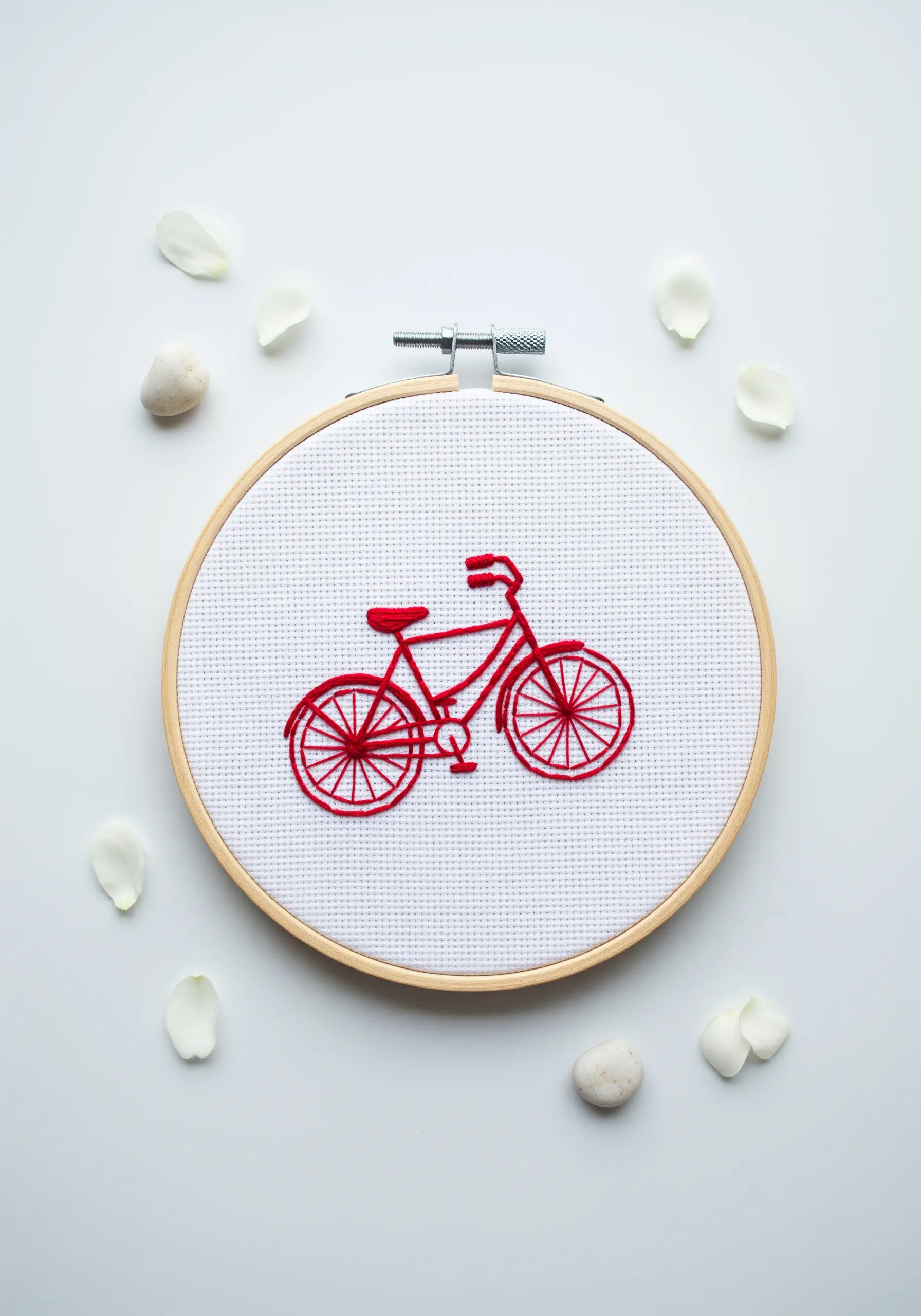 Line art embroidery of a red bicycle using backstitch and woven wheel stitches.