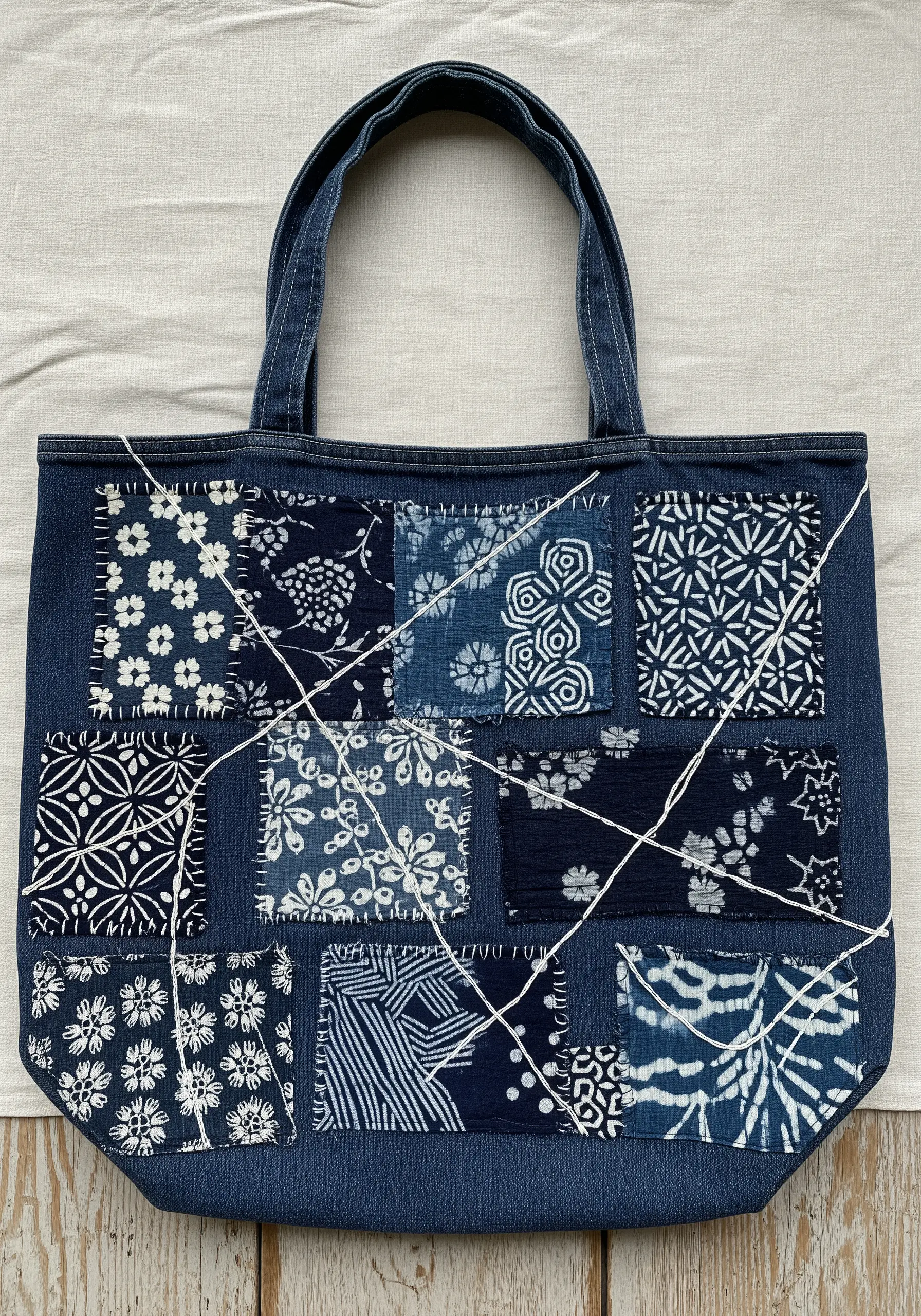 A Boro-style patchwork tote bag made with various indigo fabric scraps stitched onto denim.