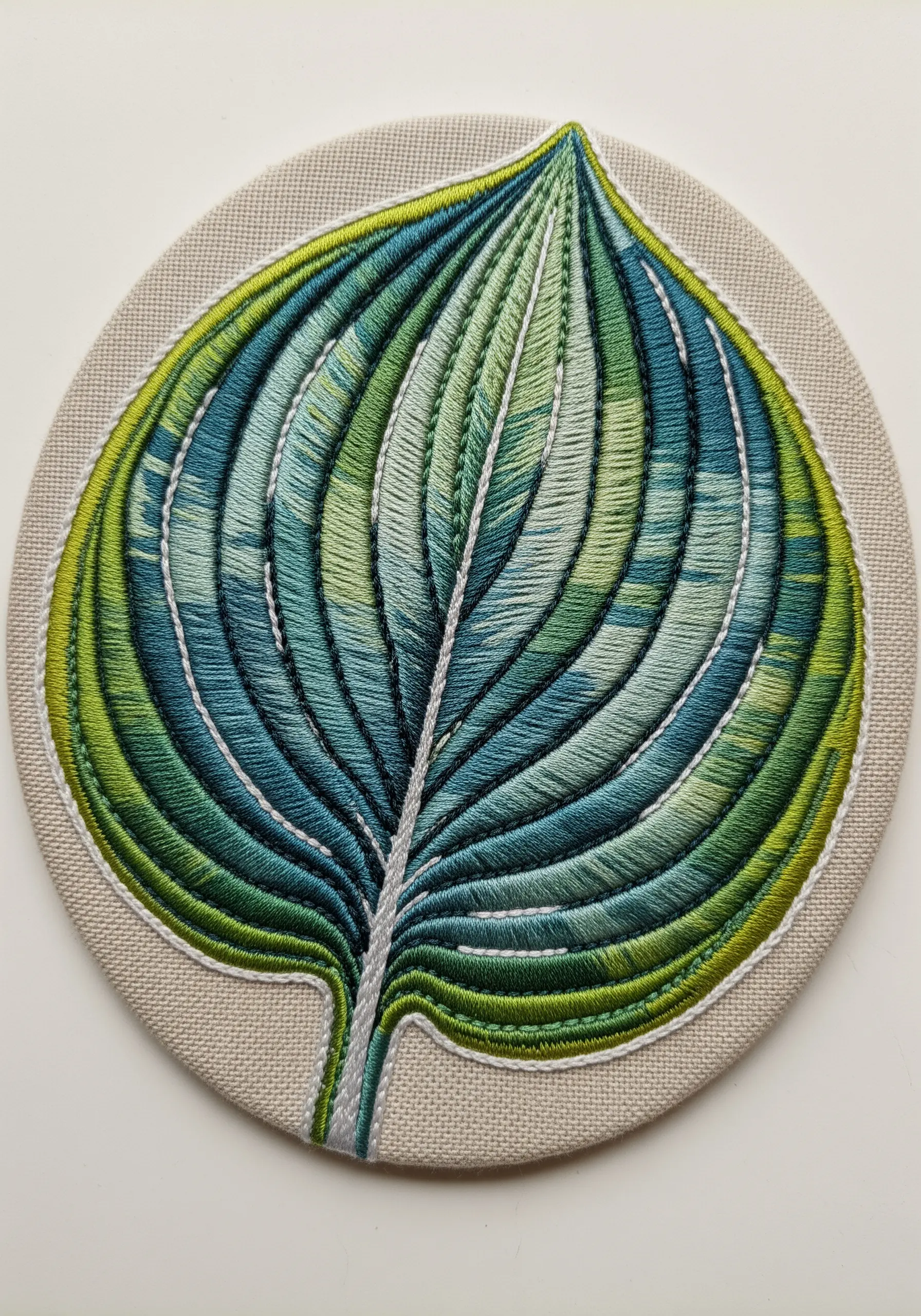 A round embroidery patch of a Hosta leaf with blue, green, and chartreuse stripes.