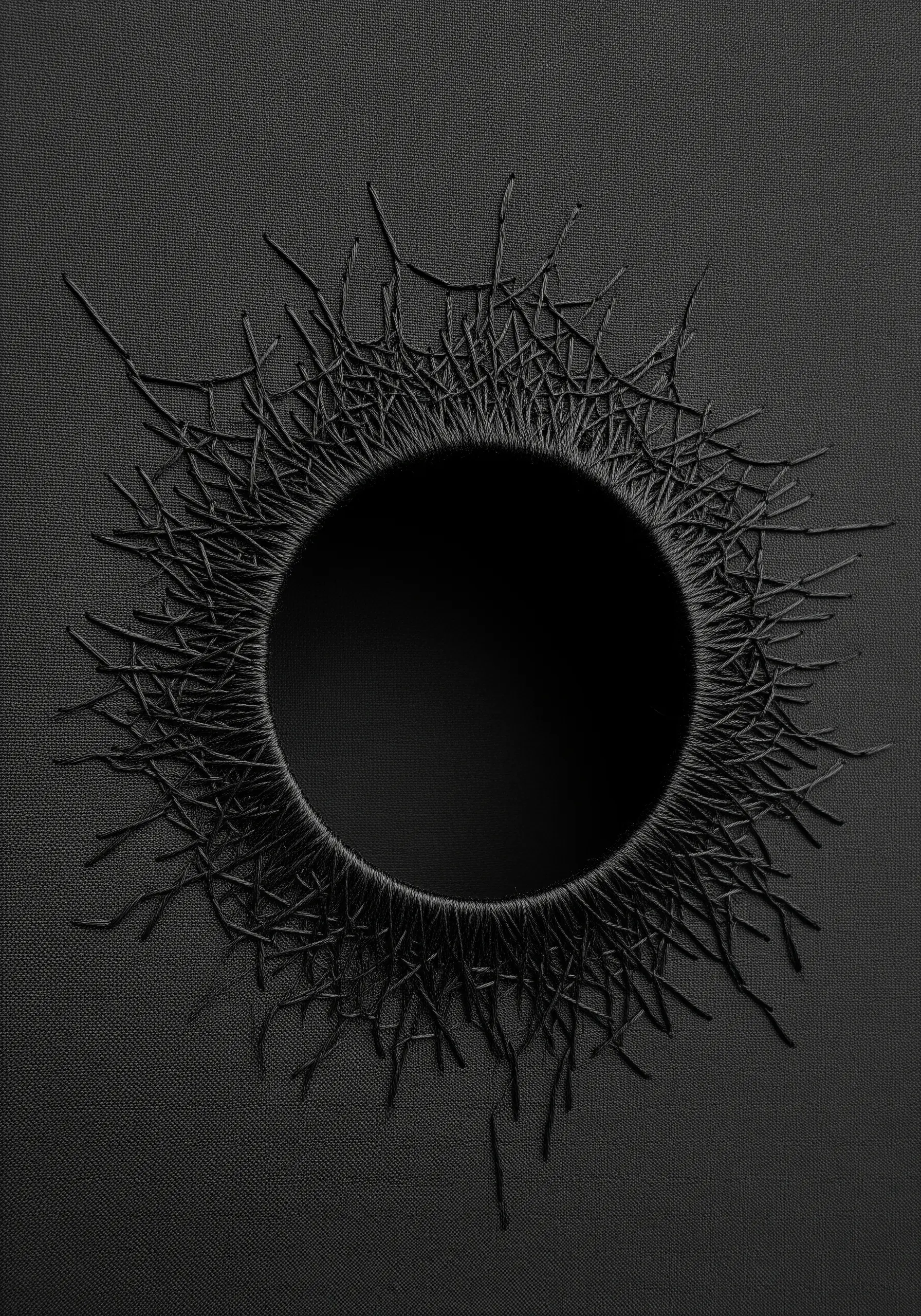 Abstract black hole stitched with black thread on black fabric, using texture for contrast.