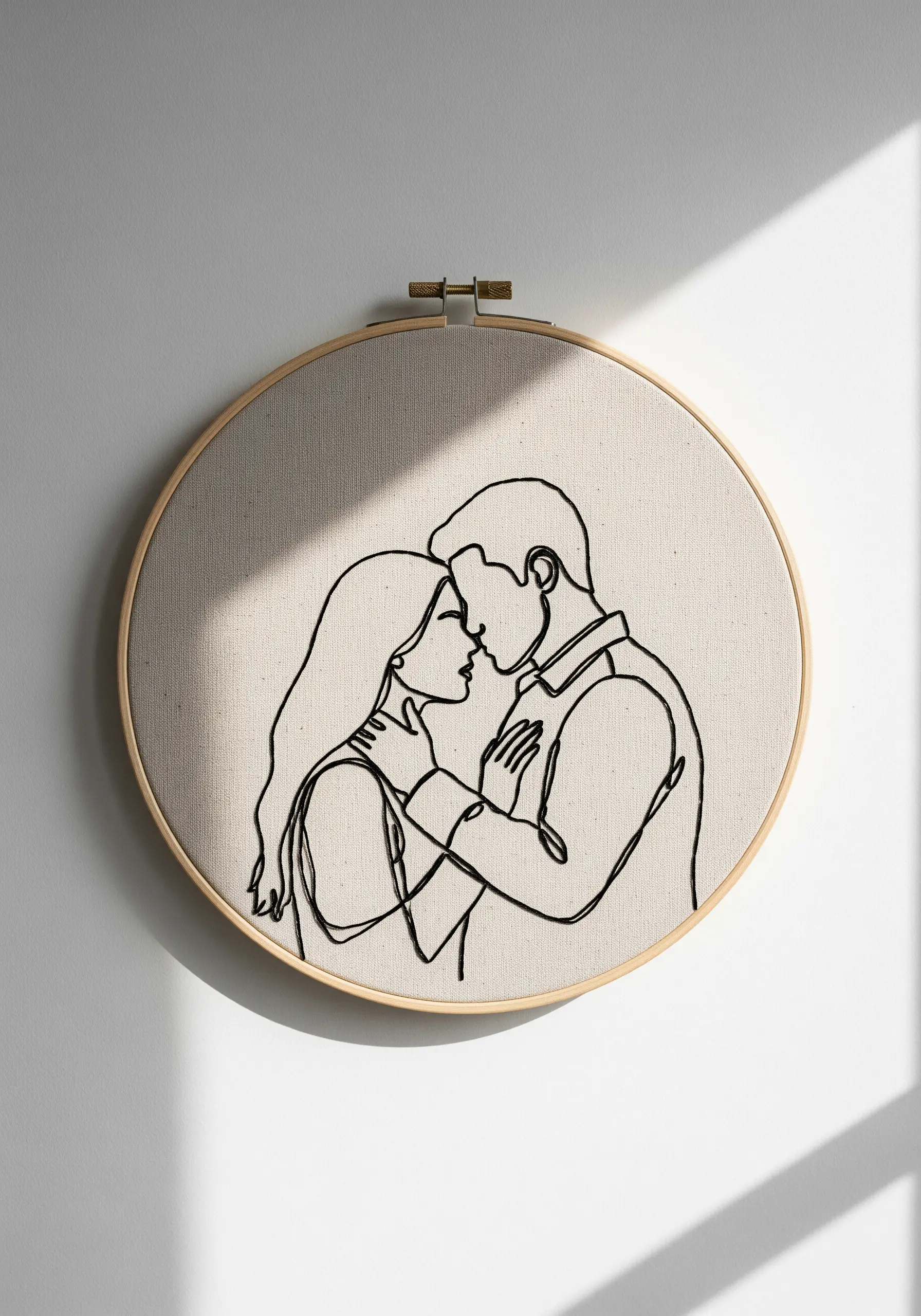 A single continuous black line embroidered on neutral canvas to form a portrait of a couple kissing.