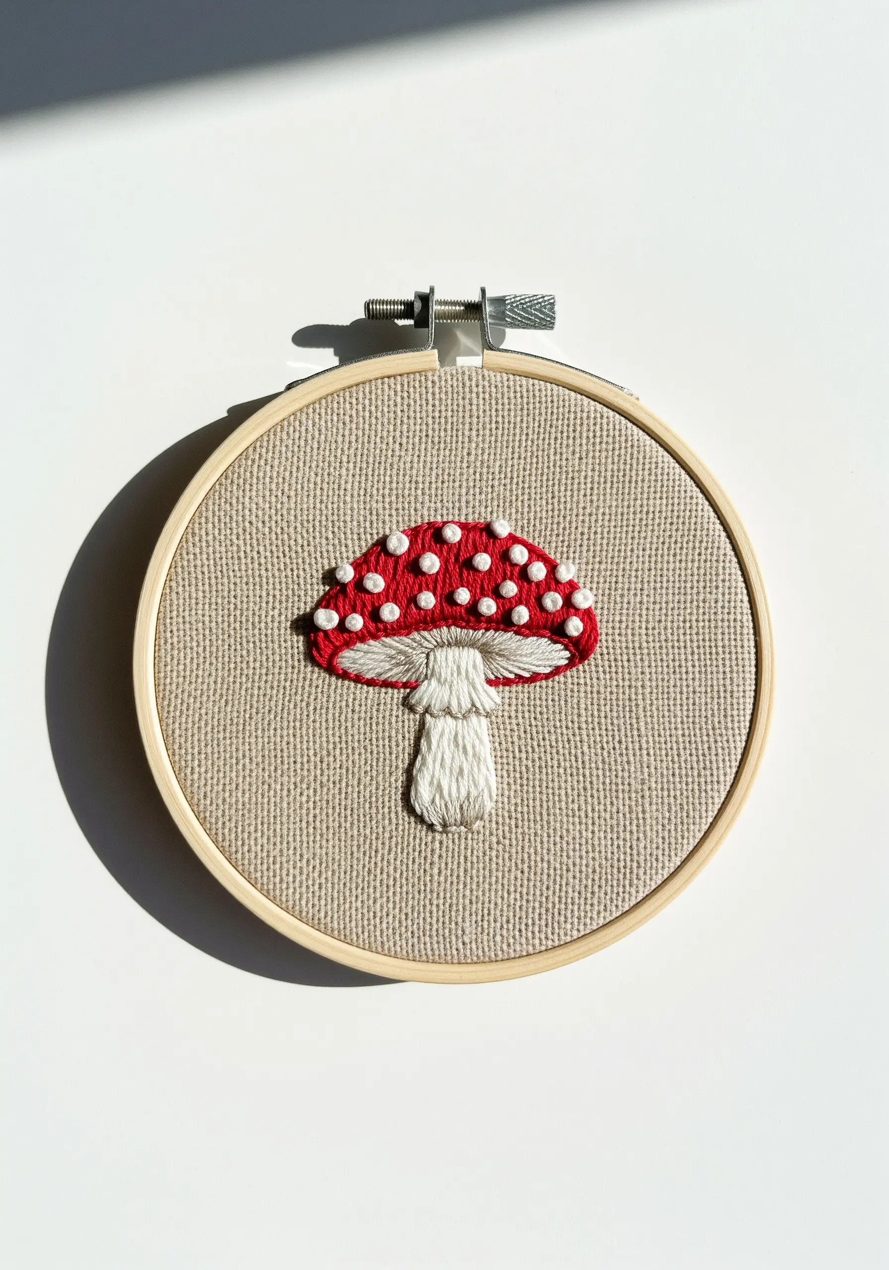 A red and white toadstool mushroom with a textured, padded satin stitch cap.