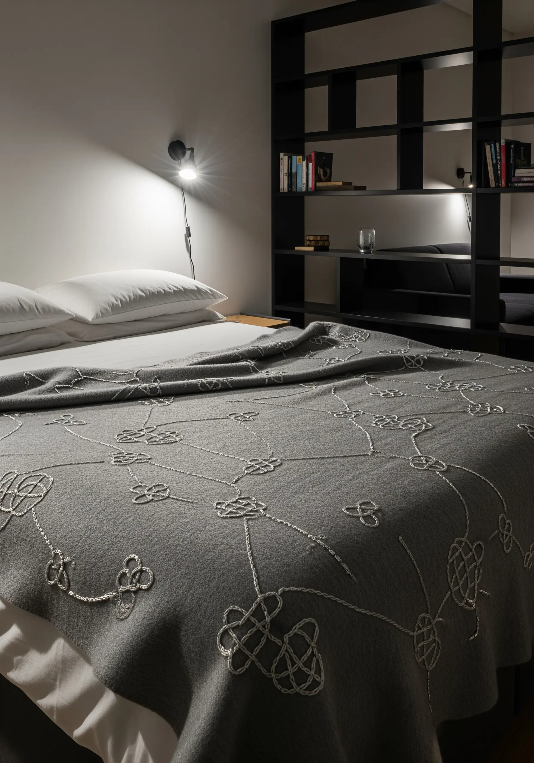 A grey wool blanket embellished with intricate, tone-on-tone textural embroidery patterns.