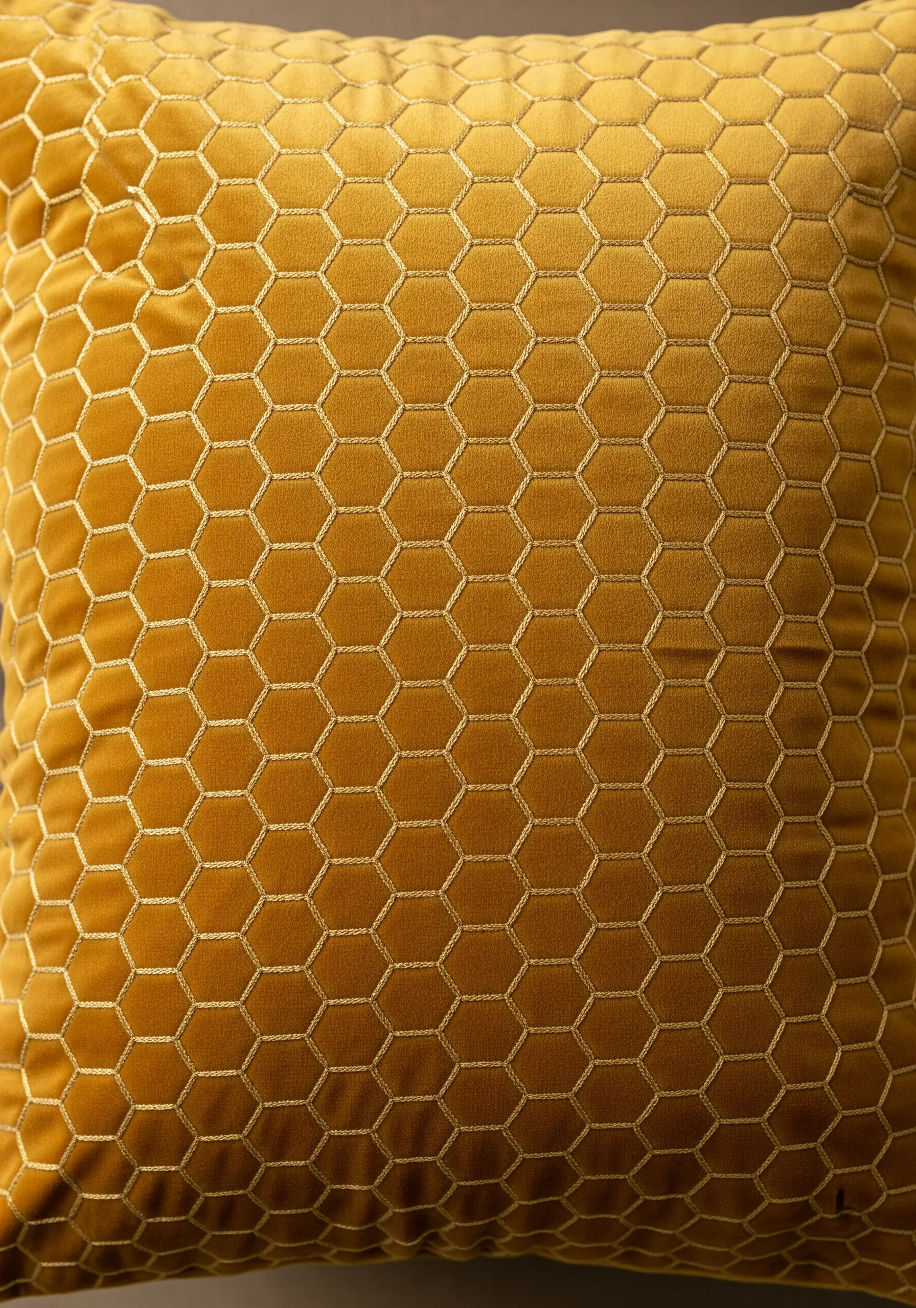 Gold thread honeycomb pattern stitched onto a gold velvet cushion.