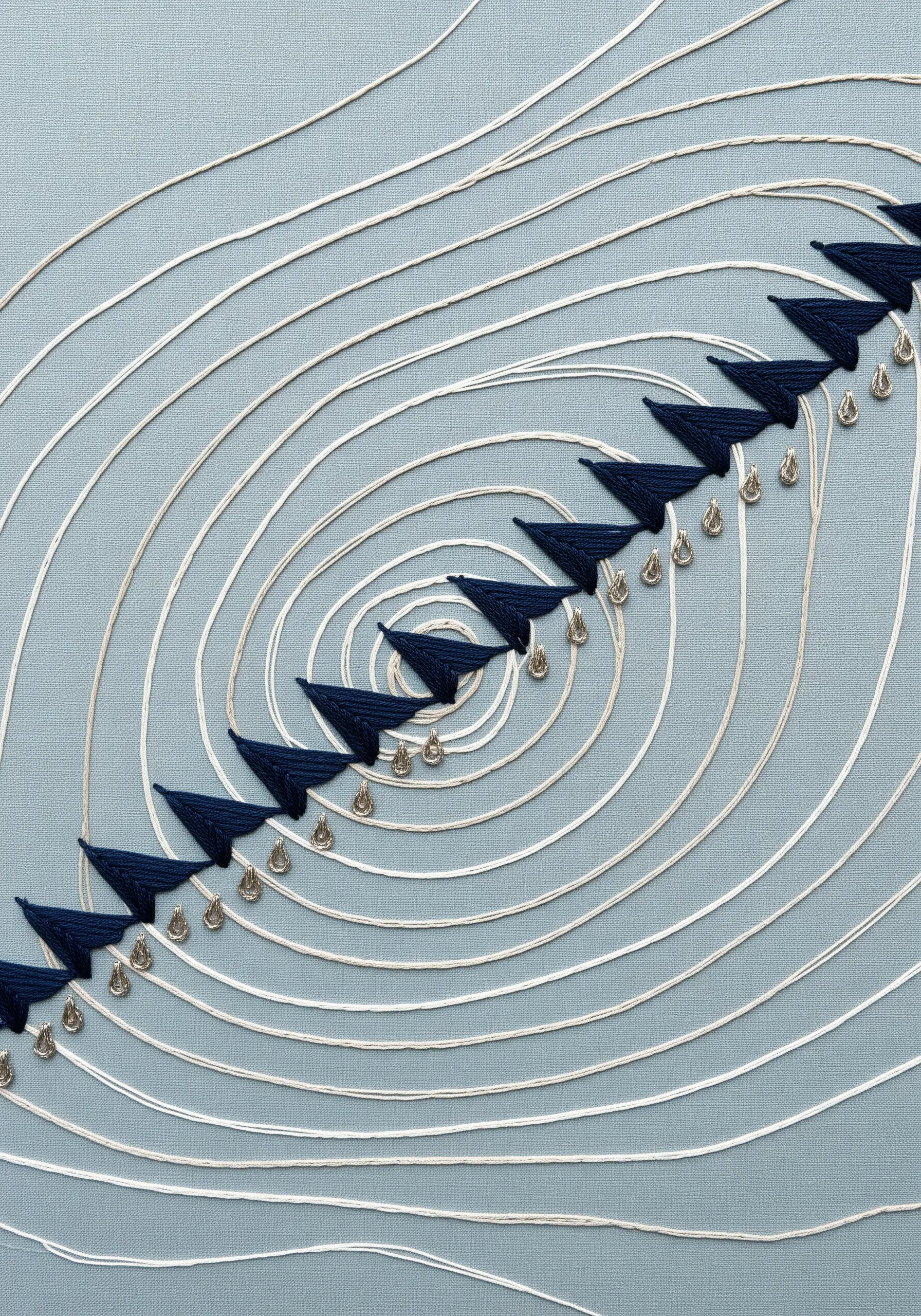 Abstract sound wave embroidery with concentric white circles and navy blue accents.