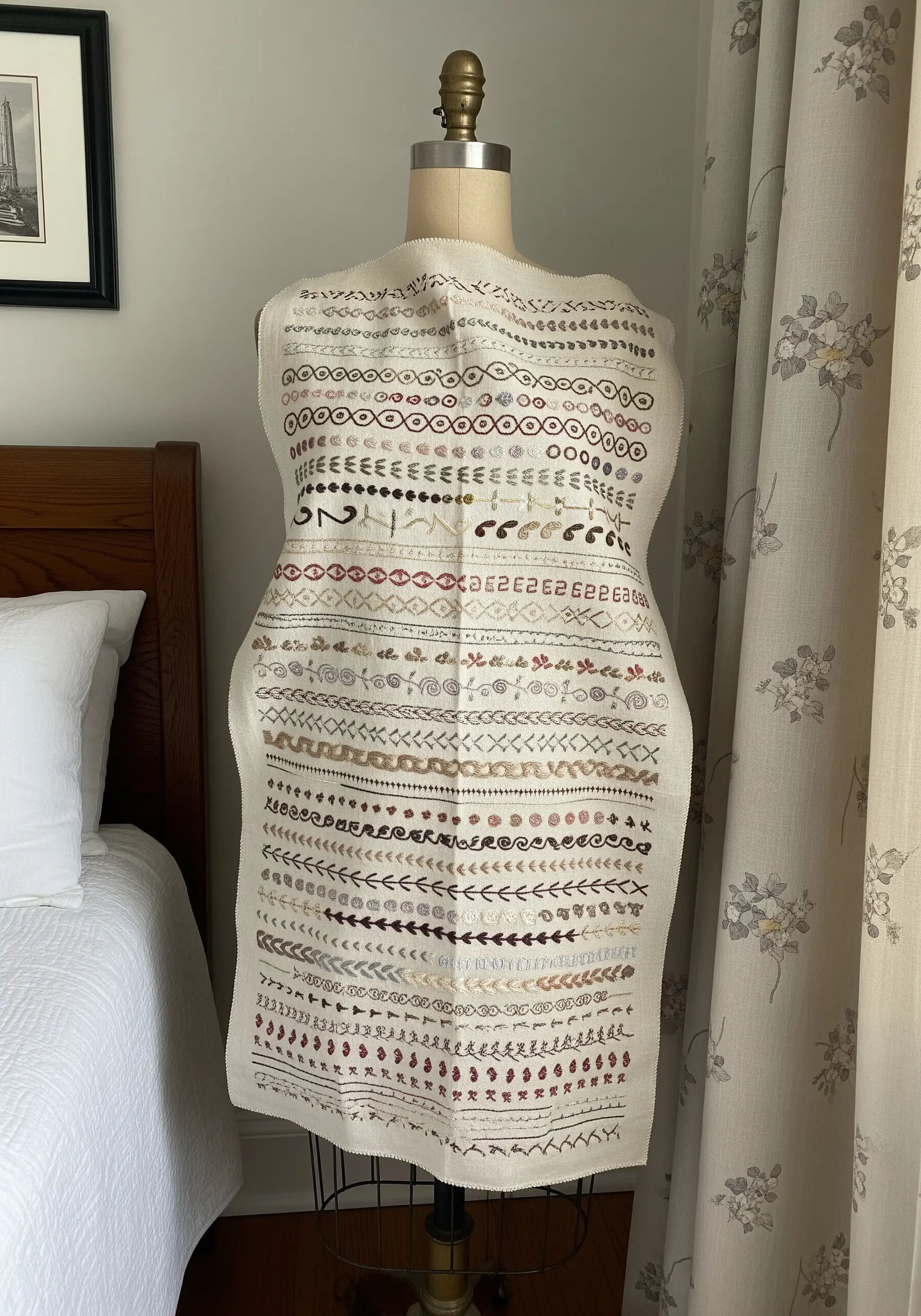 A detailed embroidery sampler with organized rows of different stitches, draped over a dress form.