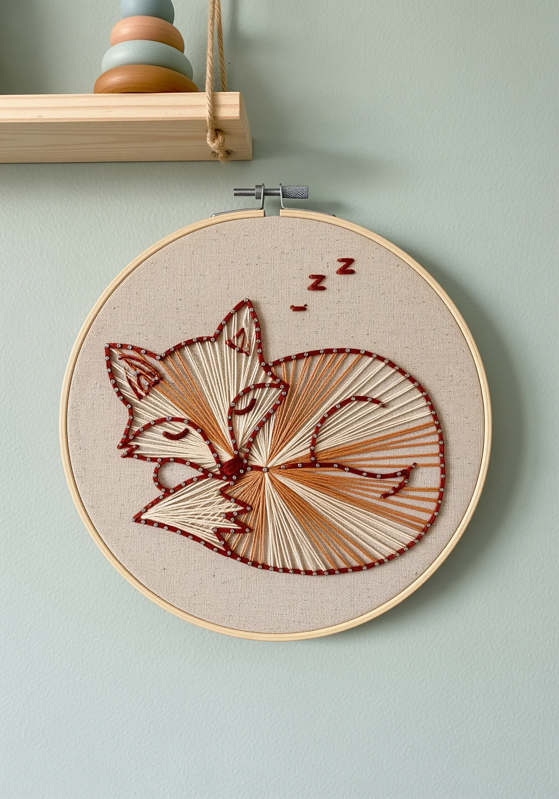 Sleeping fox embroidery hoop with radiating satin stitches in orange and white.